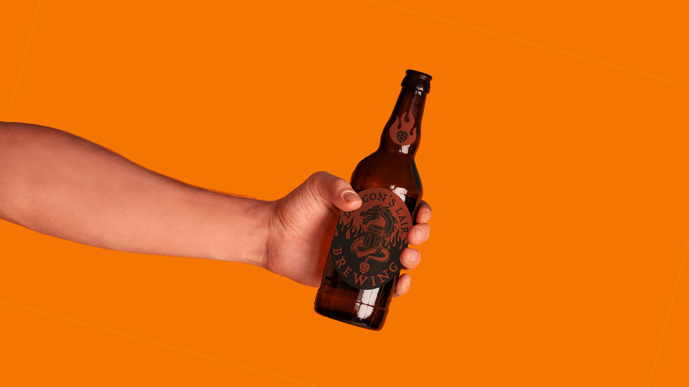 A person holding a brown glass beer bottle with a black label featuring a dragon and flames, against an orange background.