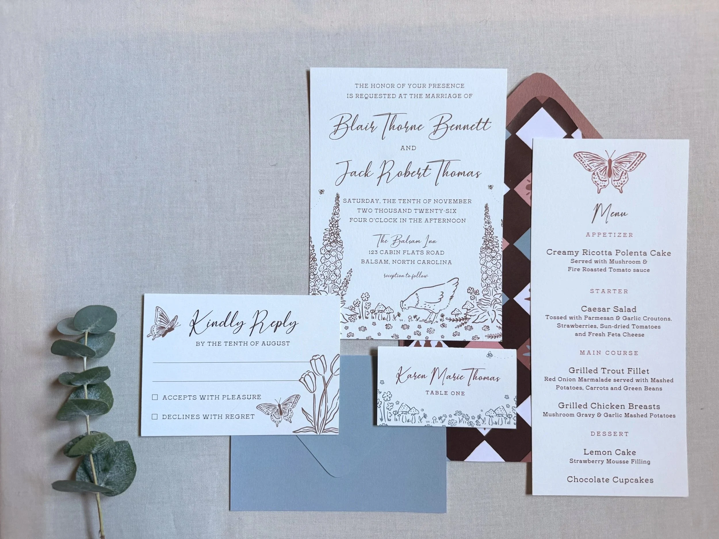 Wedding invitation set including a main invitation, RSVP card, and menu card, along with a sprig of eucalyptus leaves.