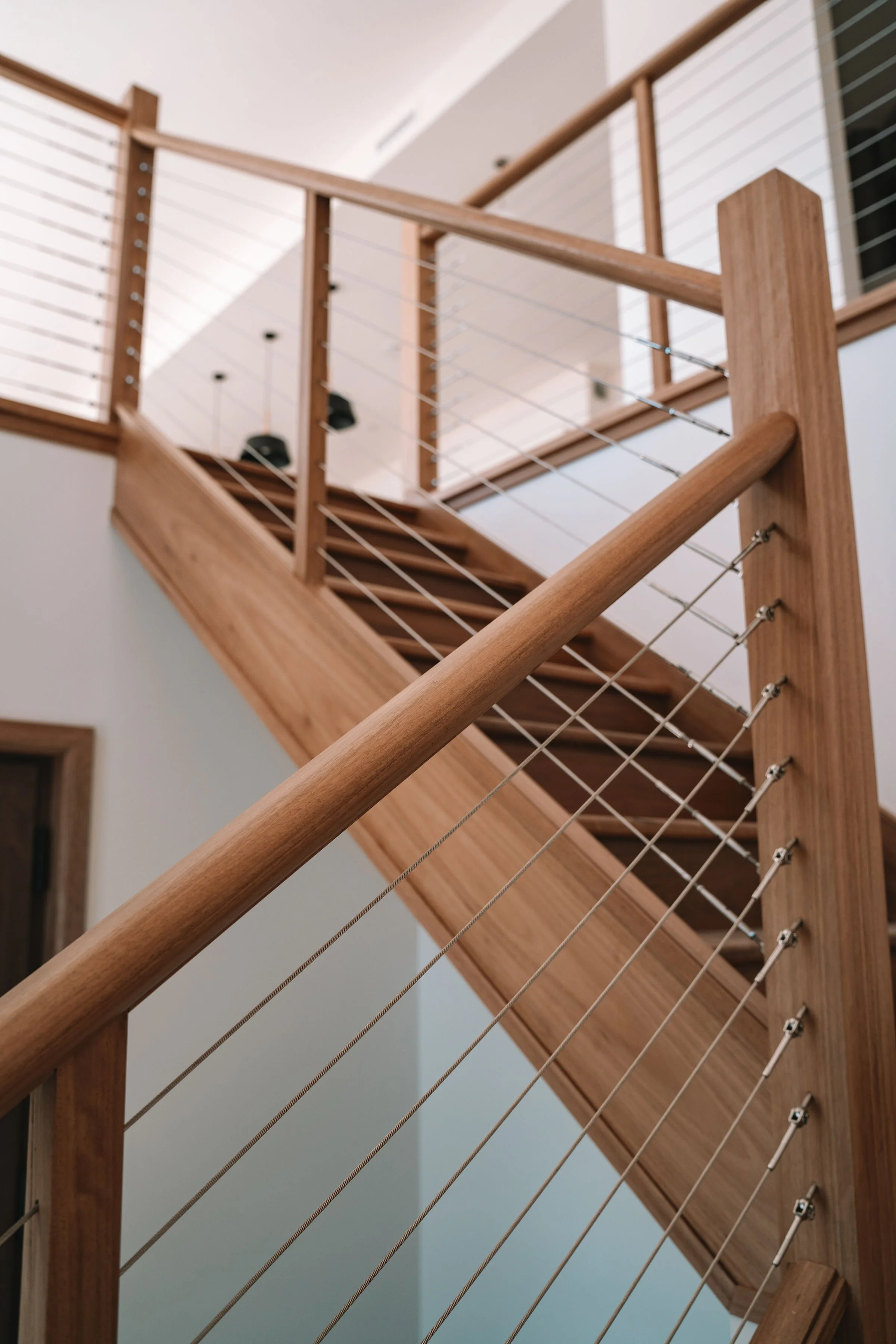 Wooden staircase with cable railing in a modern home interior.