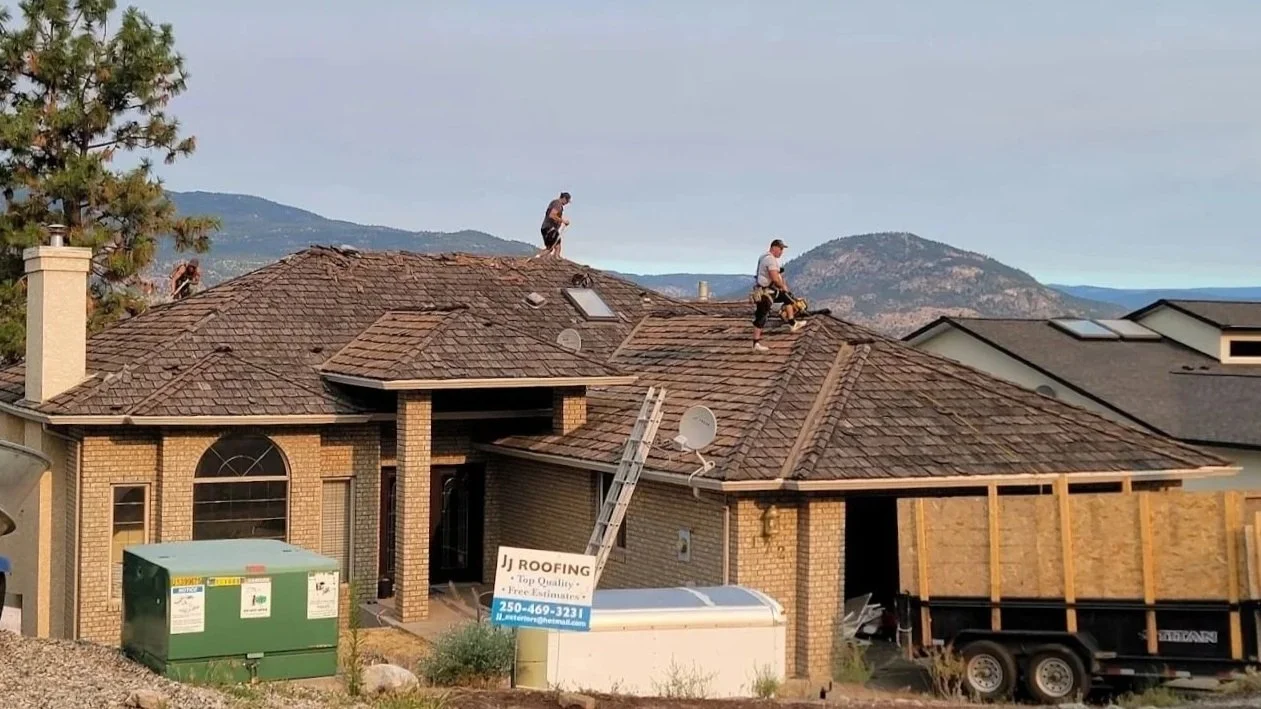 Professional roofing crew installing new asphalt shingles on a residential home.