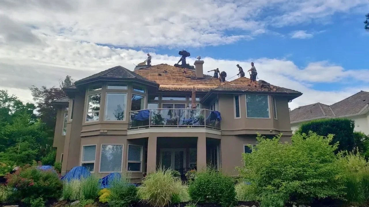 Roof replacement in progress with safety equipment and workers on roof.