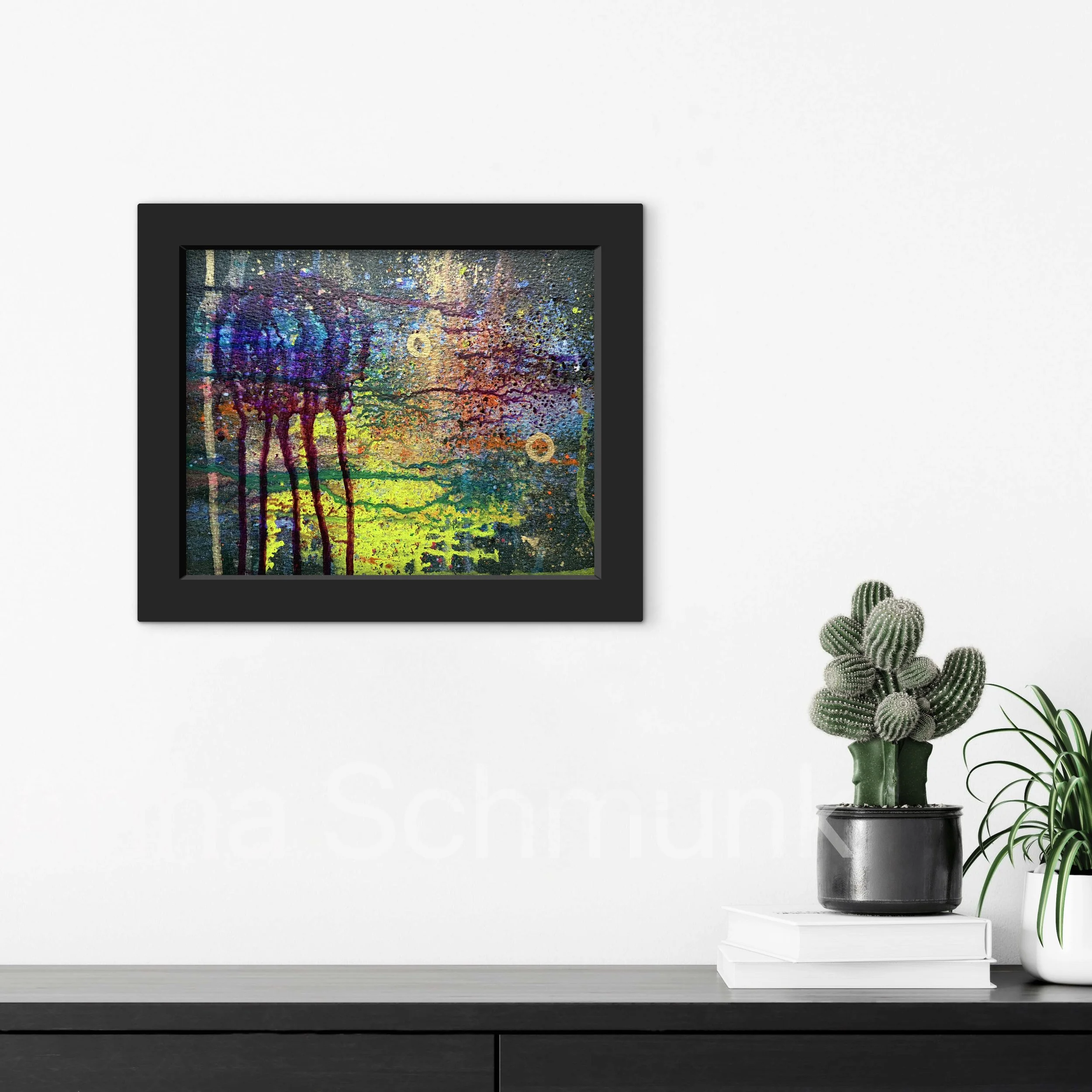 Abstract colorful painting in a black frame hung on a white wall, with potted cactus and a green leafy plant on a black shelf below.