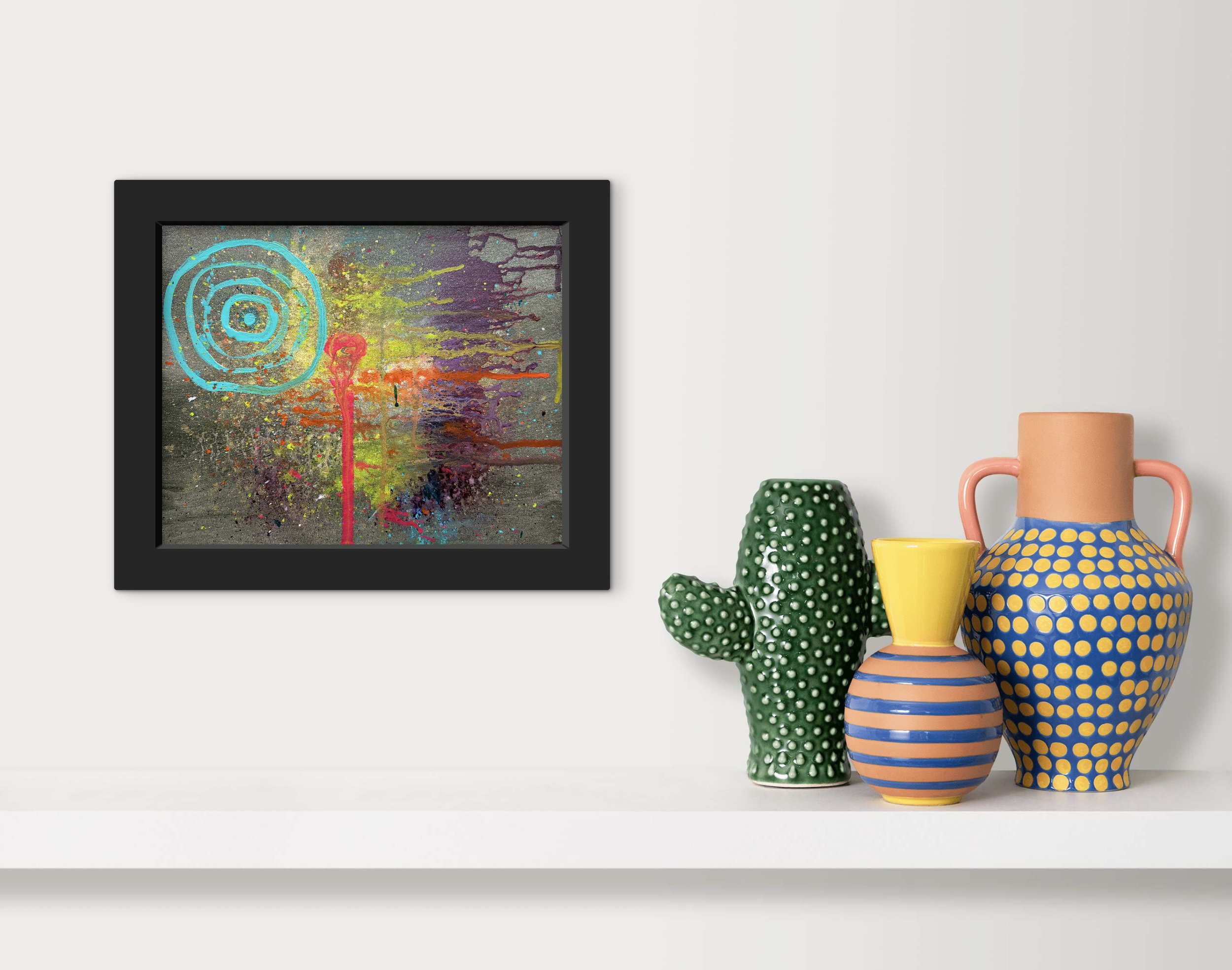 Colorful abstract painting in a black frame and decorative pottery vases on a white shelf against a white wall.