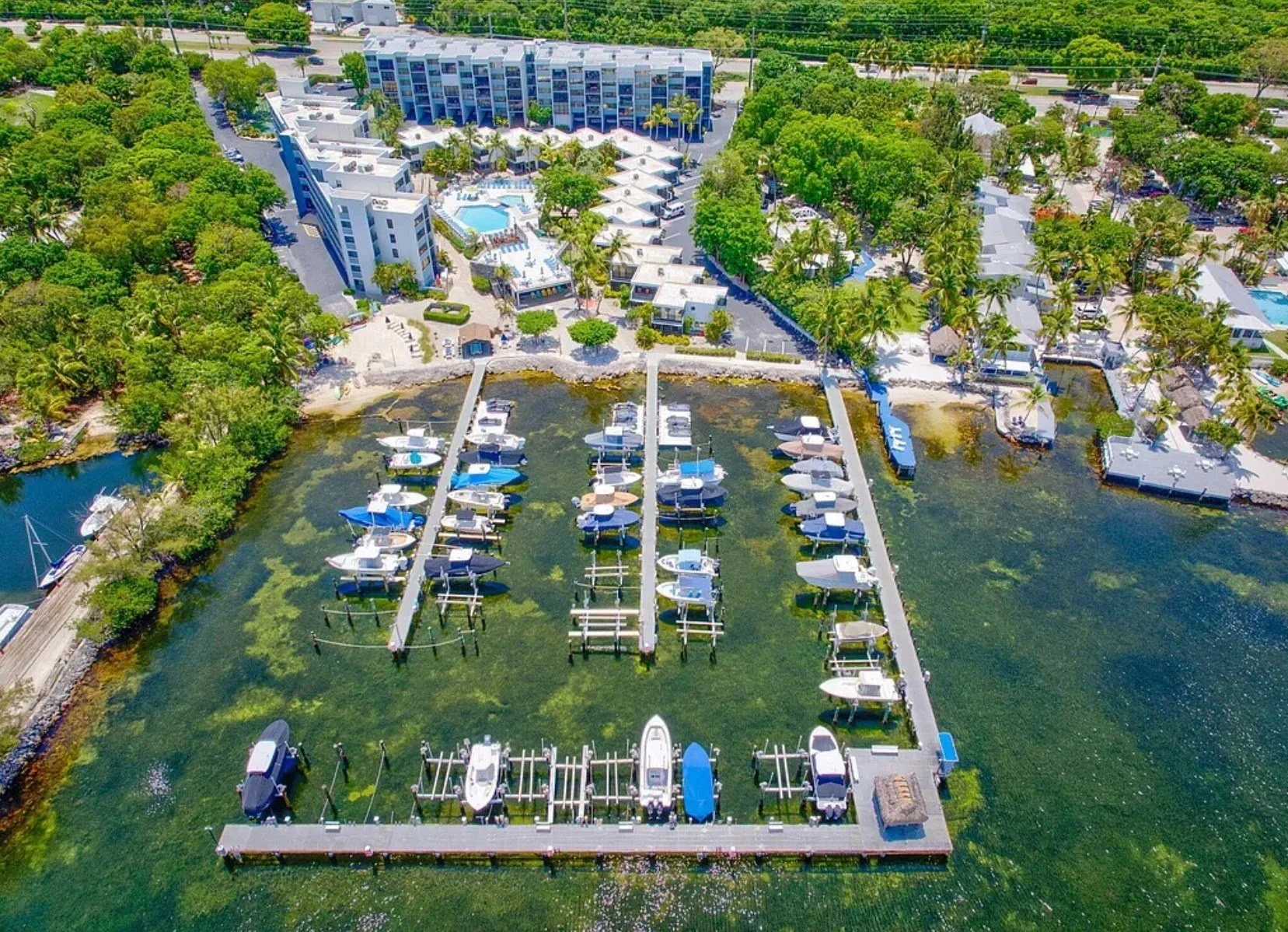 Aerial view of Moon Bay in Key Largo, a waterfront community on Blackwater Sound with a marina, heated pool, beach, kayaks, pickleball, and stunning sunset views.