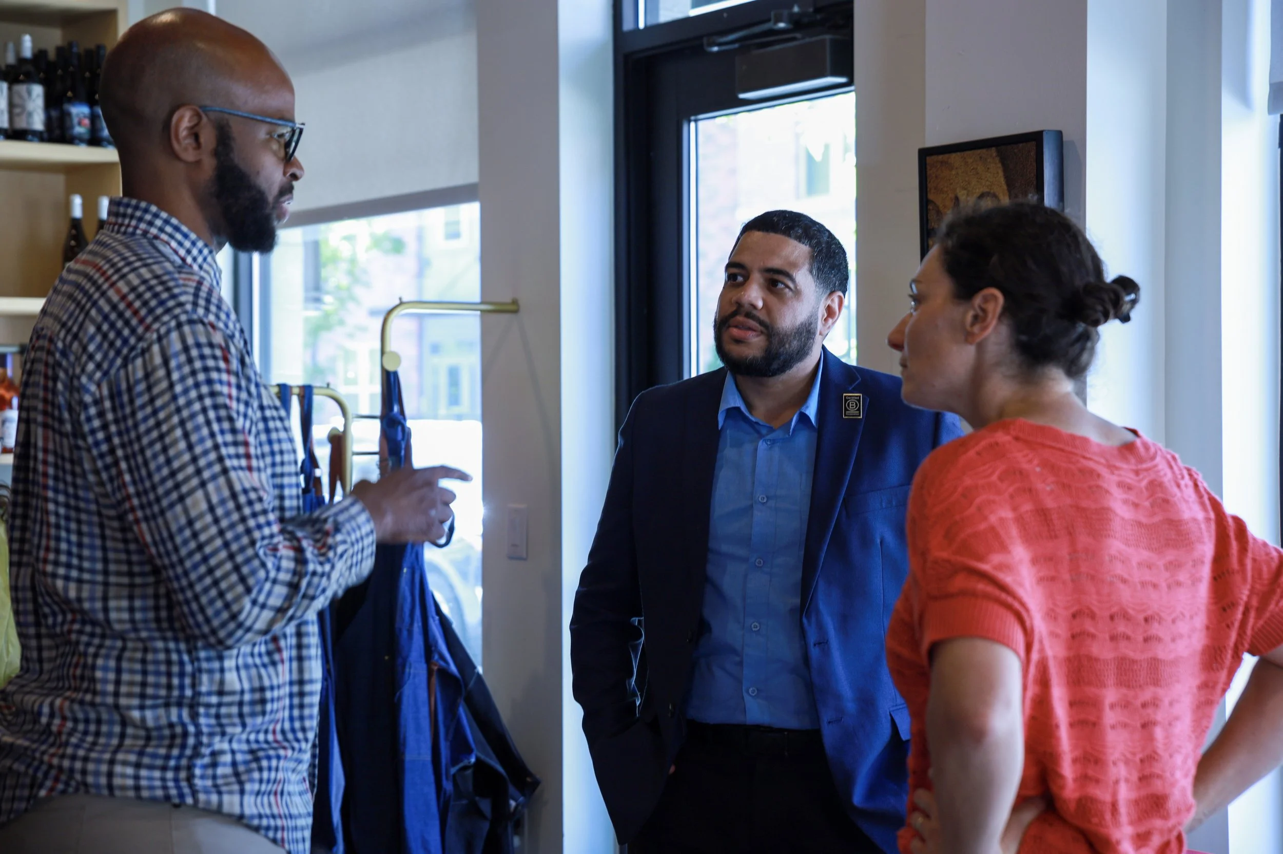 Three people having a conversation inside a store near the entrance during our Michigan Good Business Summit.