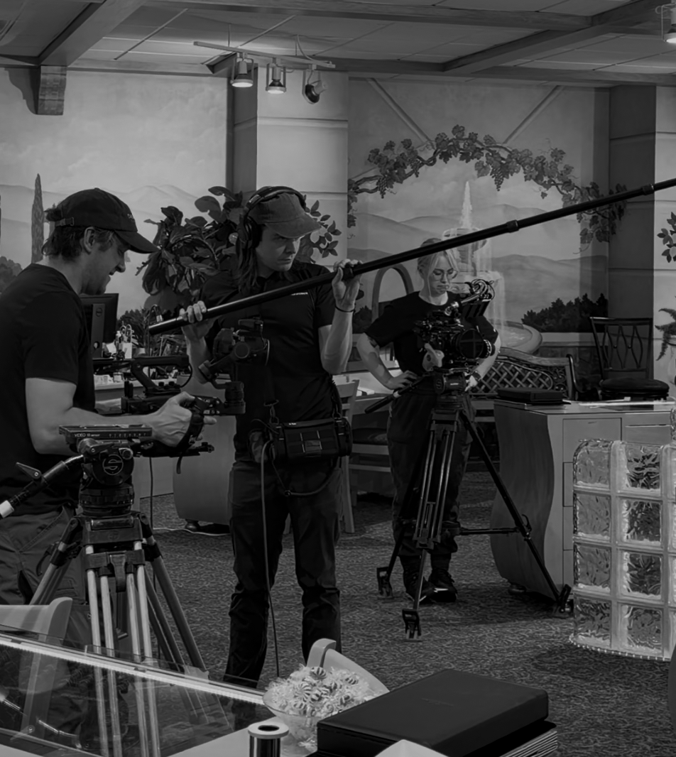 Filmmakers working with camera and boom microphone in a studio with a painted mural wall.
