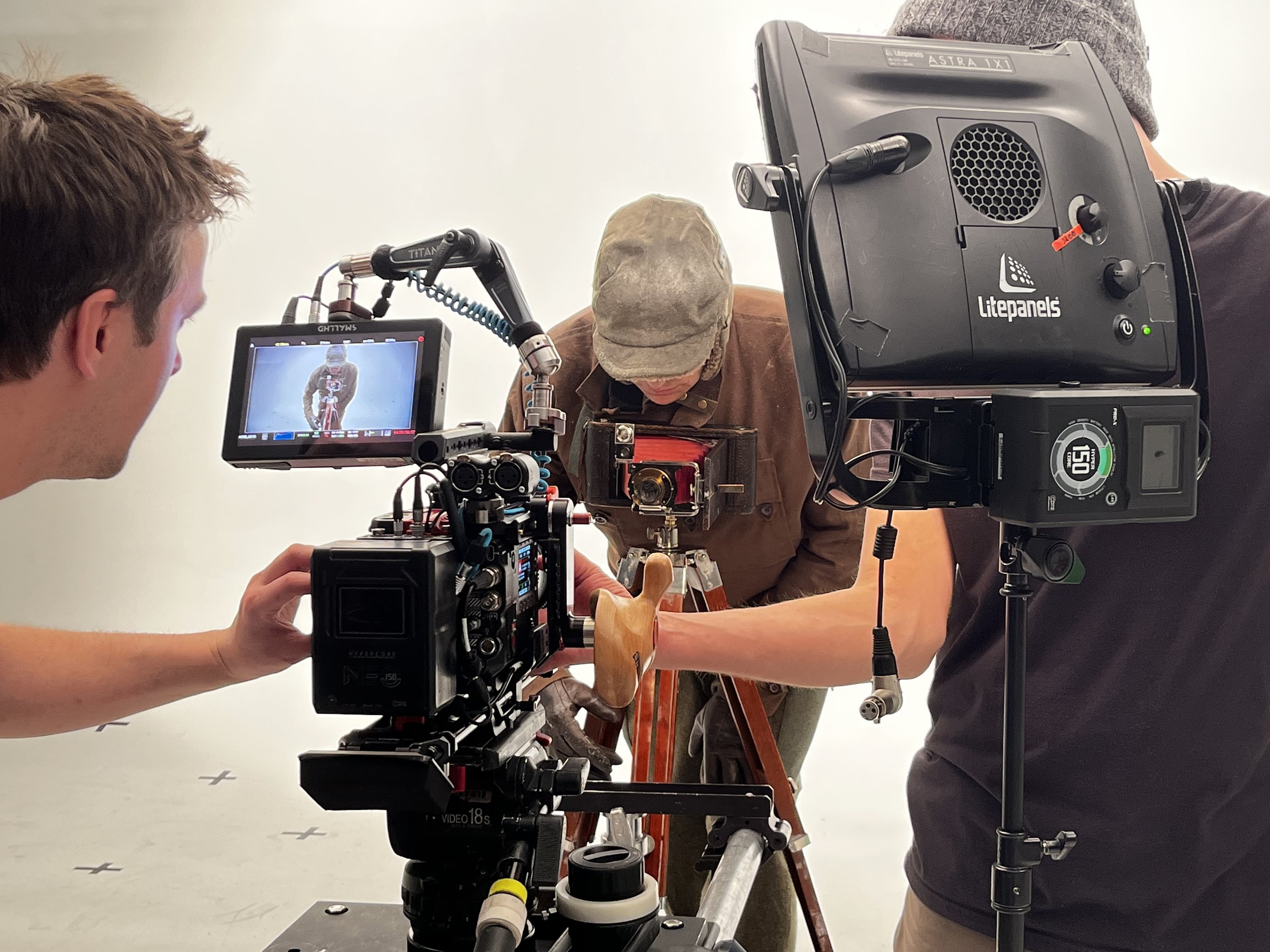 Film crew filming a cyclist in a studio with professional camera equipment.