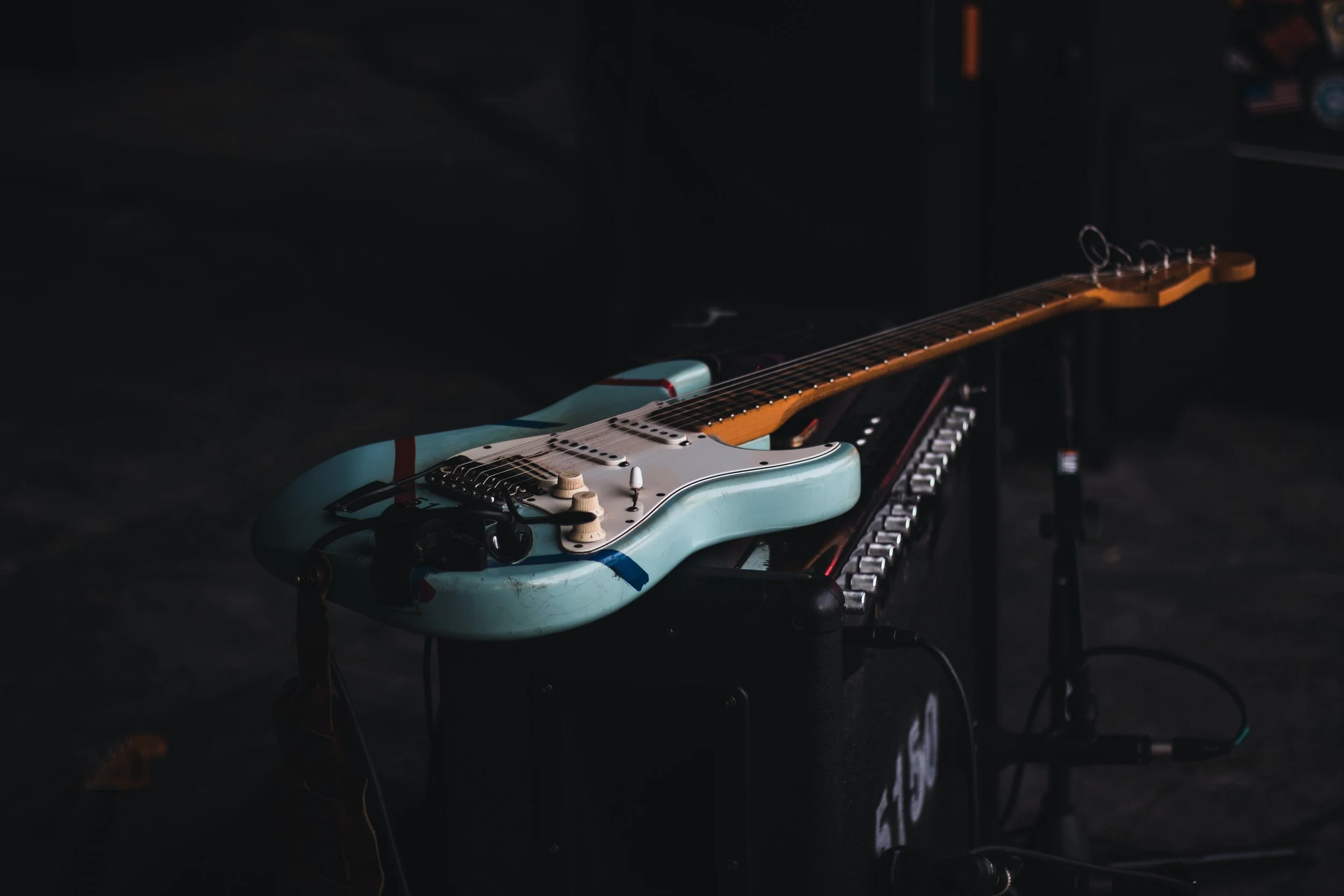 An electric guitar resting on a pedalboard in a dark room.