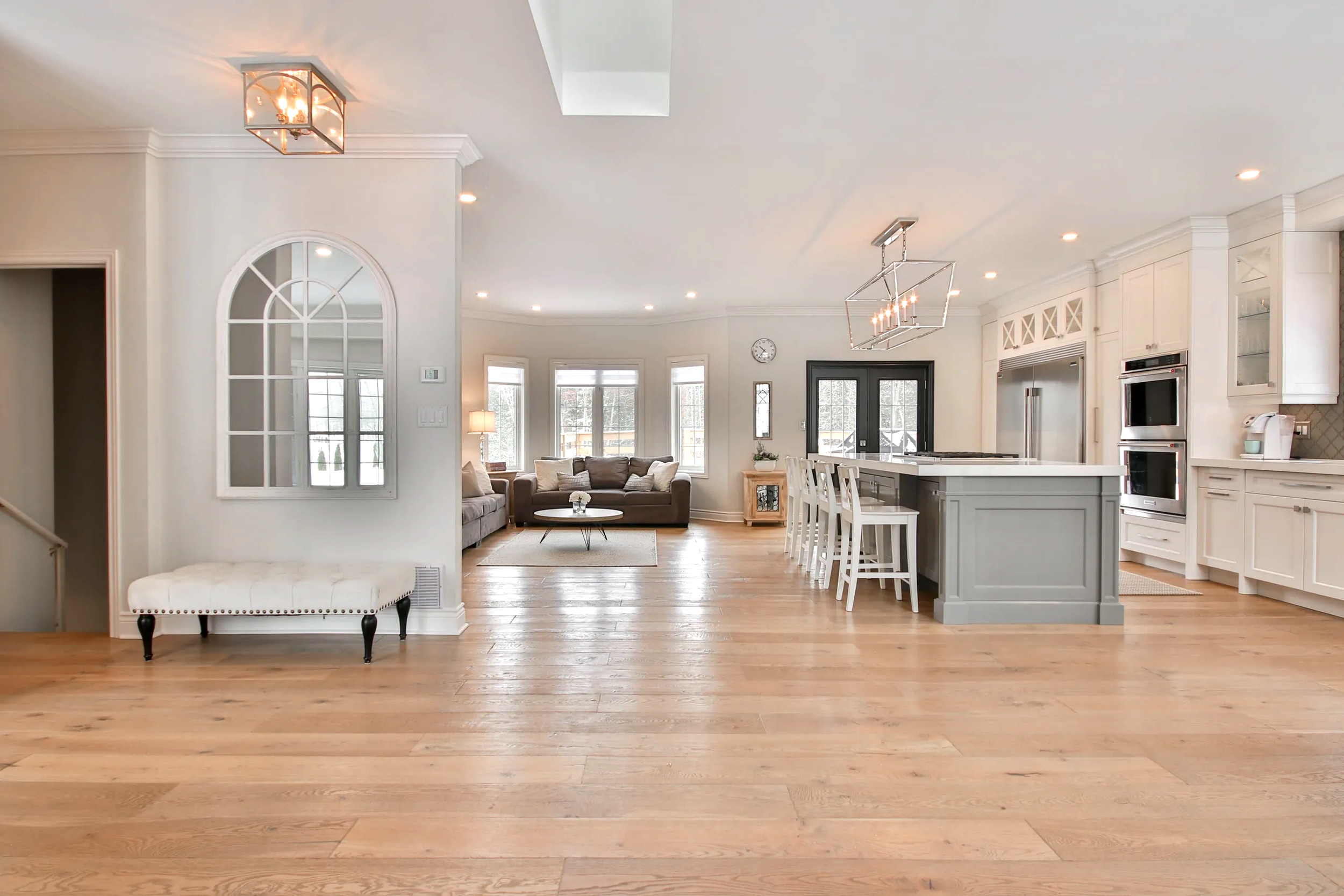 Open concept kitchen and living room with hardwood floors, white cabinetry, and large windows