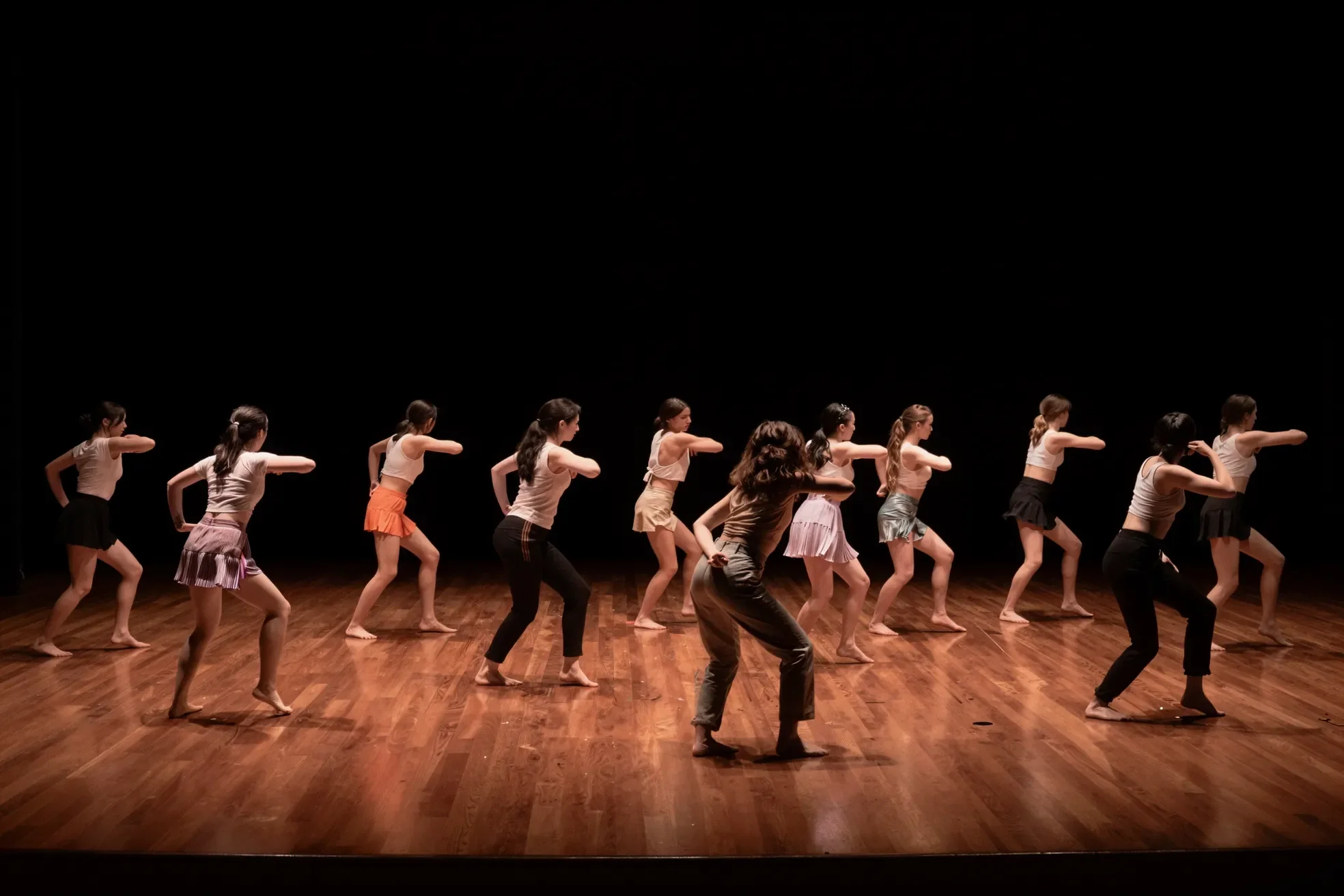 A group of dancers performing on stage with a dark background.