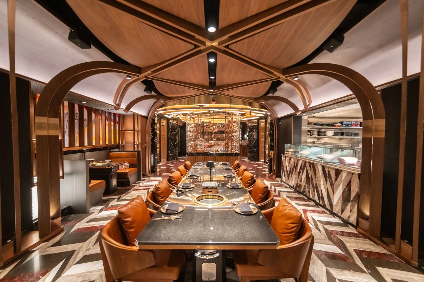 A variety of plated gourmet dishes on a wooden table, including salads, meats, and vegetable dishes, with drinks and decorative greenery.