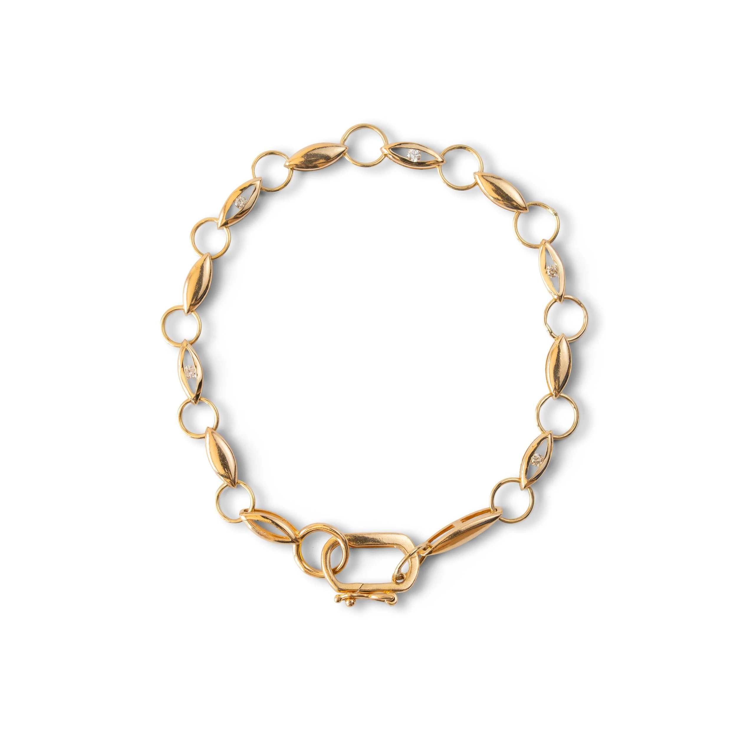 Gold link bracelet with lozenge-shaped and round links, and small gemstone accents.