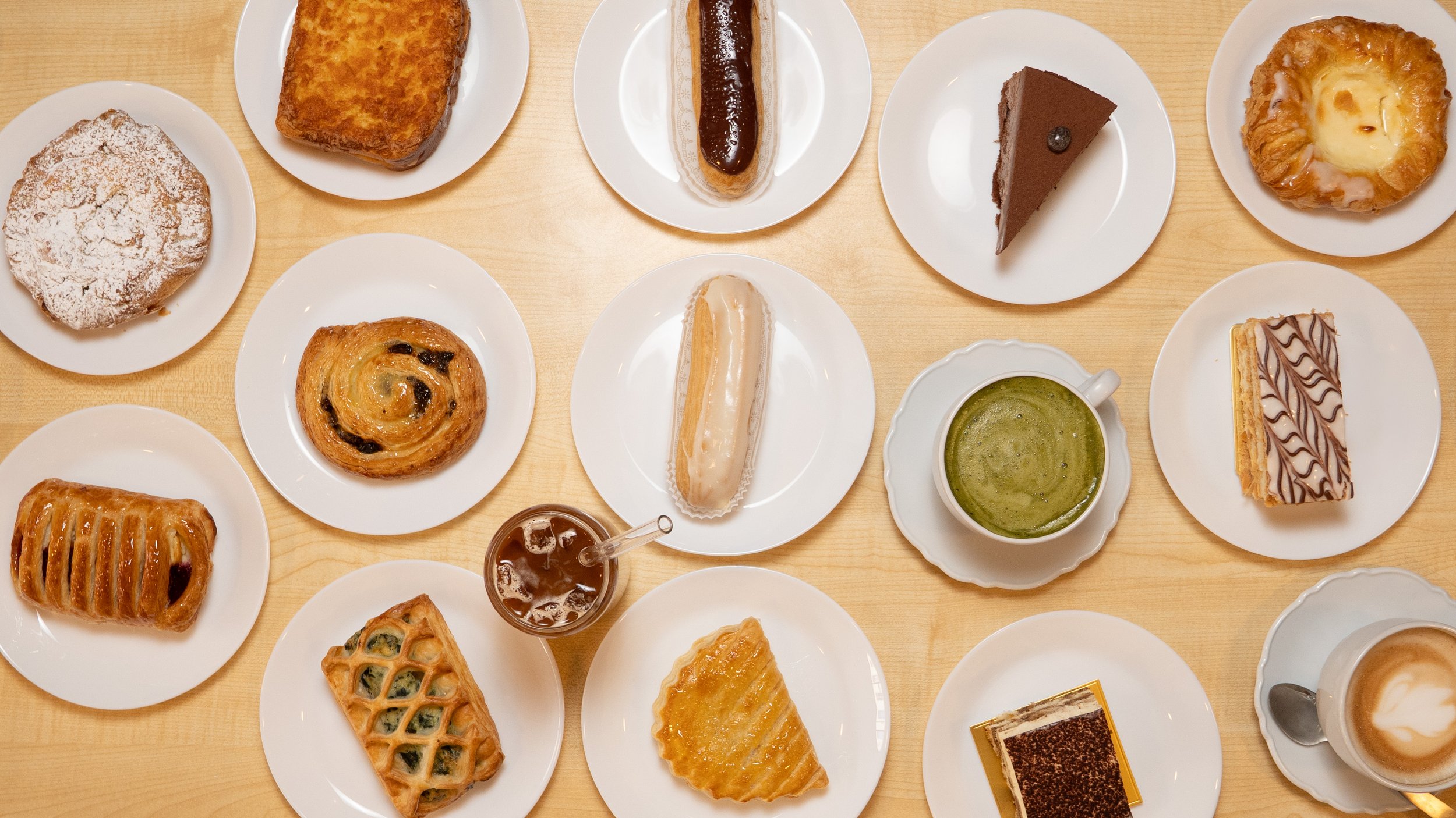 A pepperoni and cheese pizza with green herbs on a white marble table, with one slice being lifted by a hand, strings of melted cheese stretching.