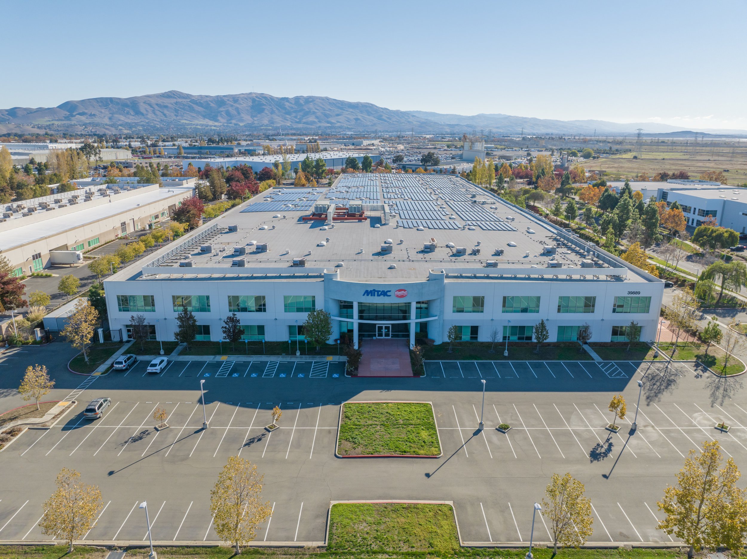 Aerial view of densely packed residential buildings with flat and mansard roofs, some with rooftop decks, in an urban neighborhood.