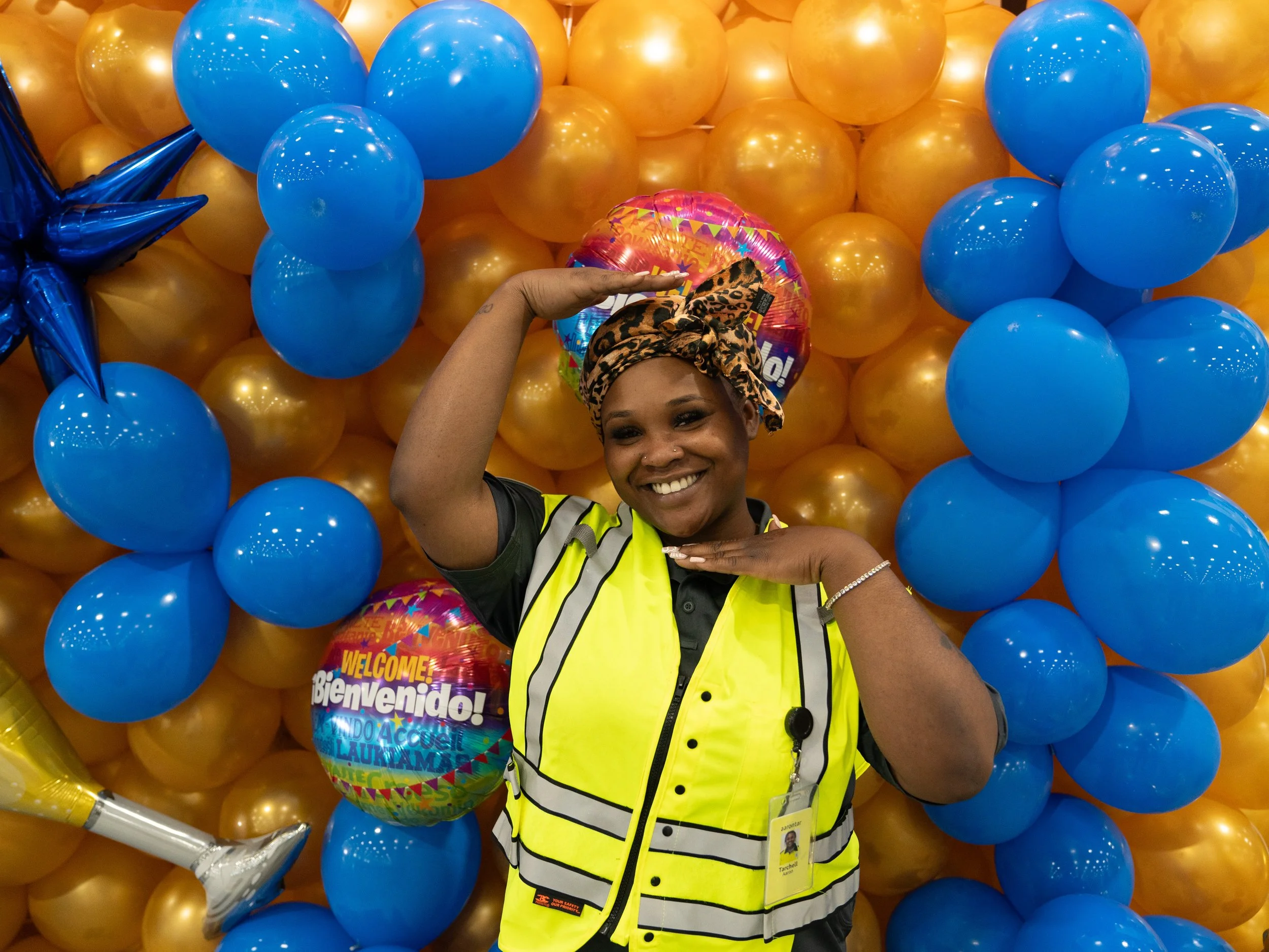 A man with dark hair and brown skin is wearing a gray zip-up jacket and standing with his arms crossed, looking confidently into the camera against a neutral background.