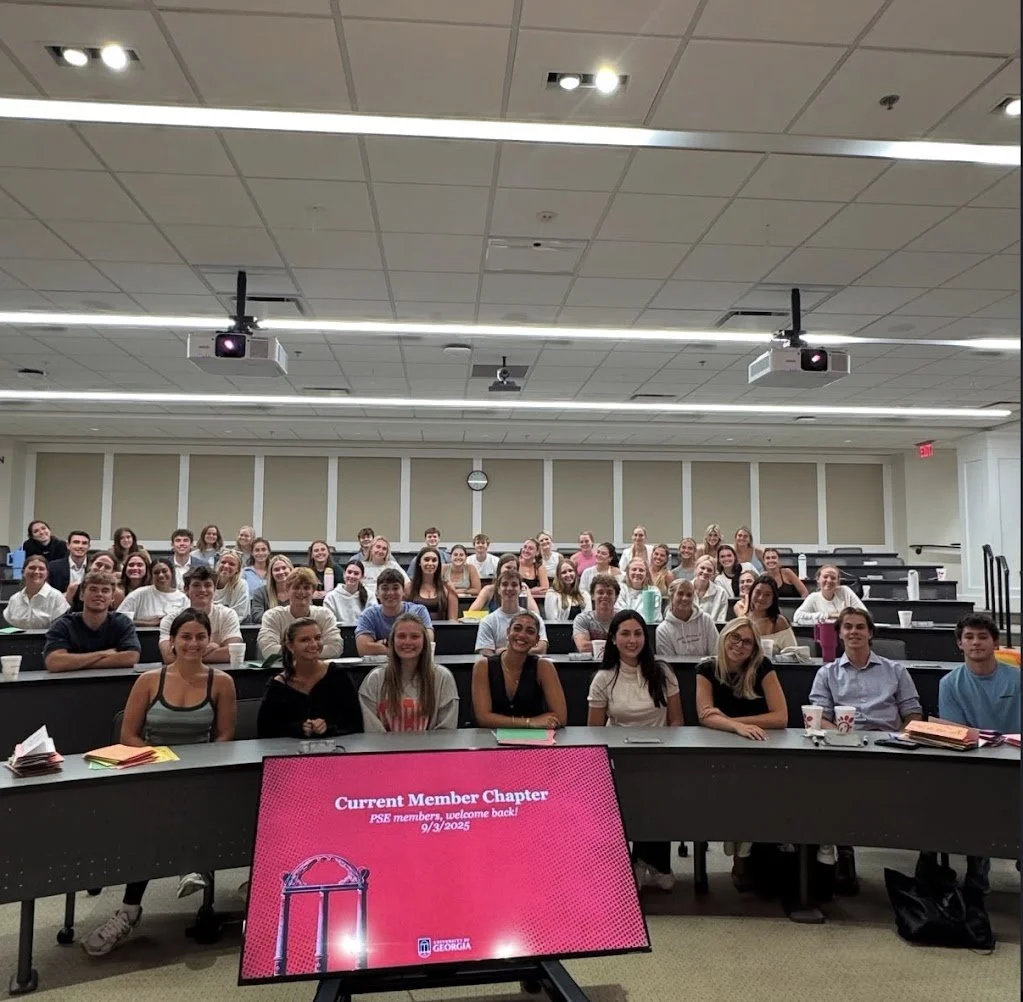 A large group of students seated in a lecture hall, facing the camera, with a digital screen in the foreground displaying 'Current Member Chapter' and a welcome message for PSU members, dated September 3, 2025.