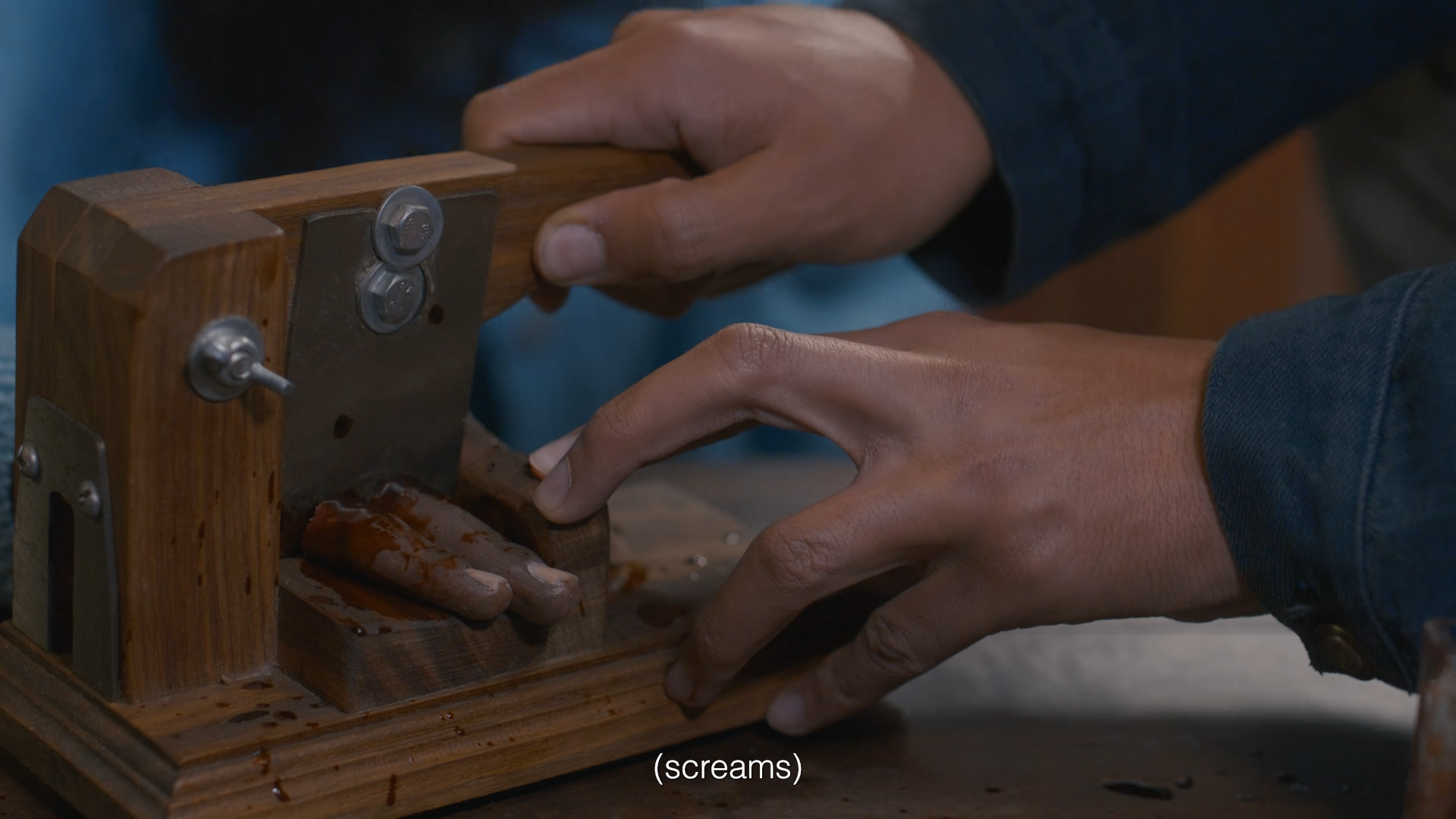 Person operating a small woodworking machine with wooden hands and metal screws, with some liquid spilling onto the surface.