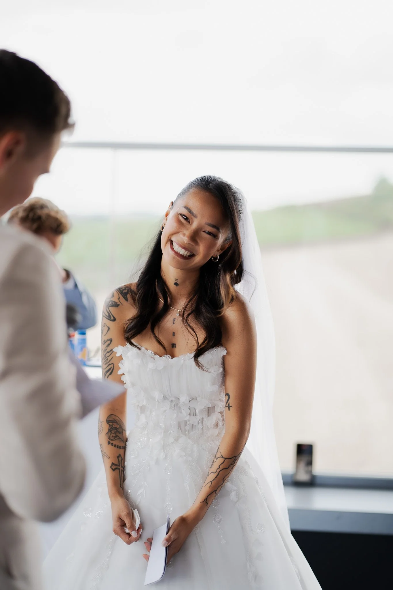 Eine lächelnde Frau in einem weißen Brautkleid bei einer Hochzeit.