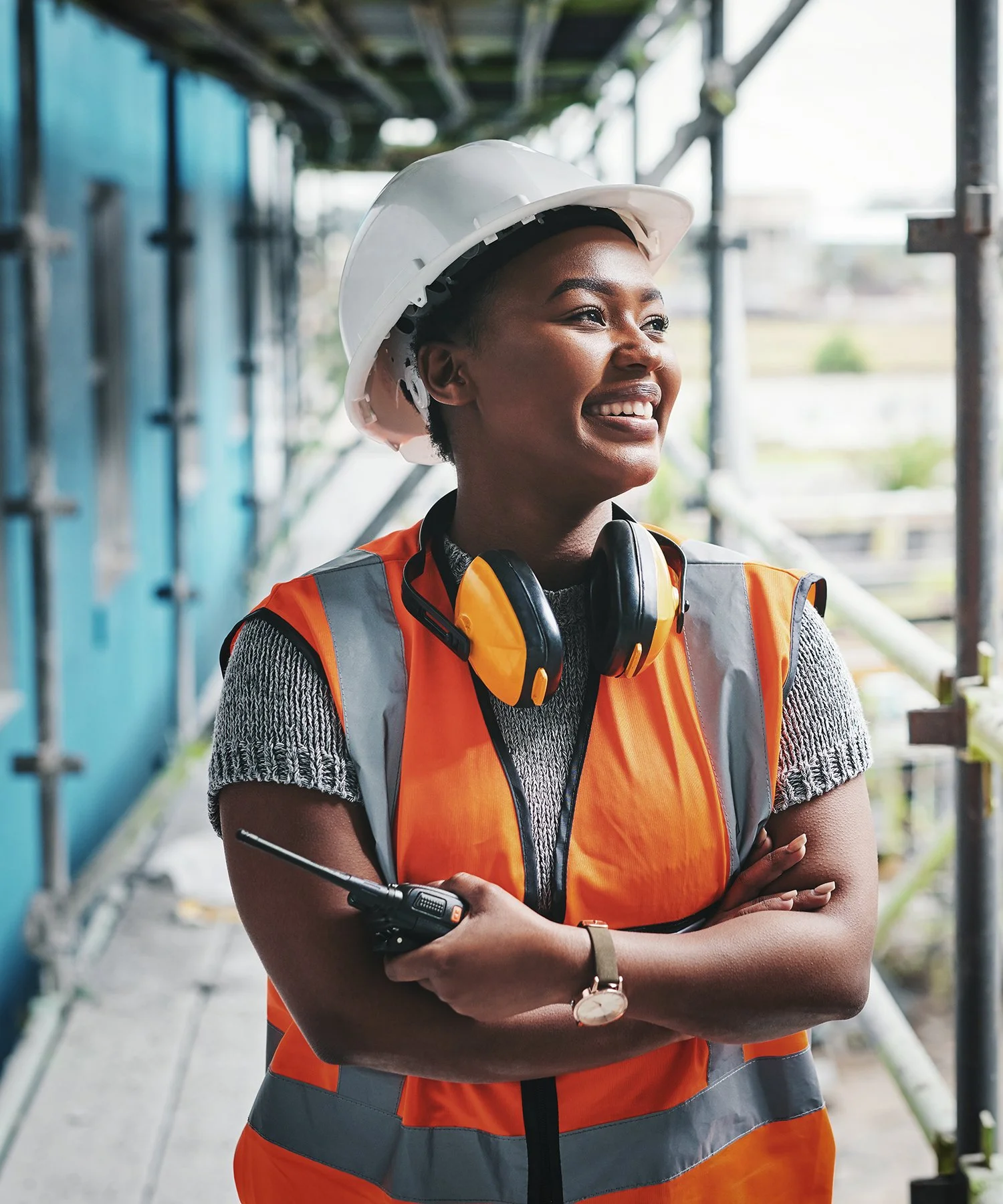 Construction worker wearing a white hard hat and an orange safety vest on a job site.