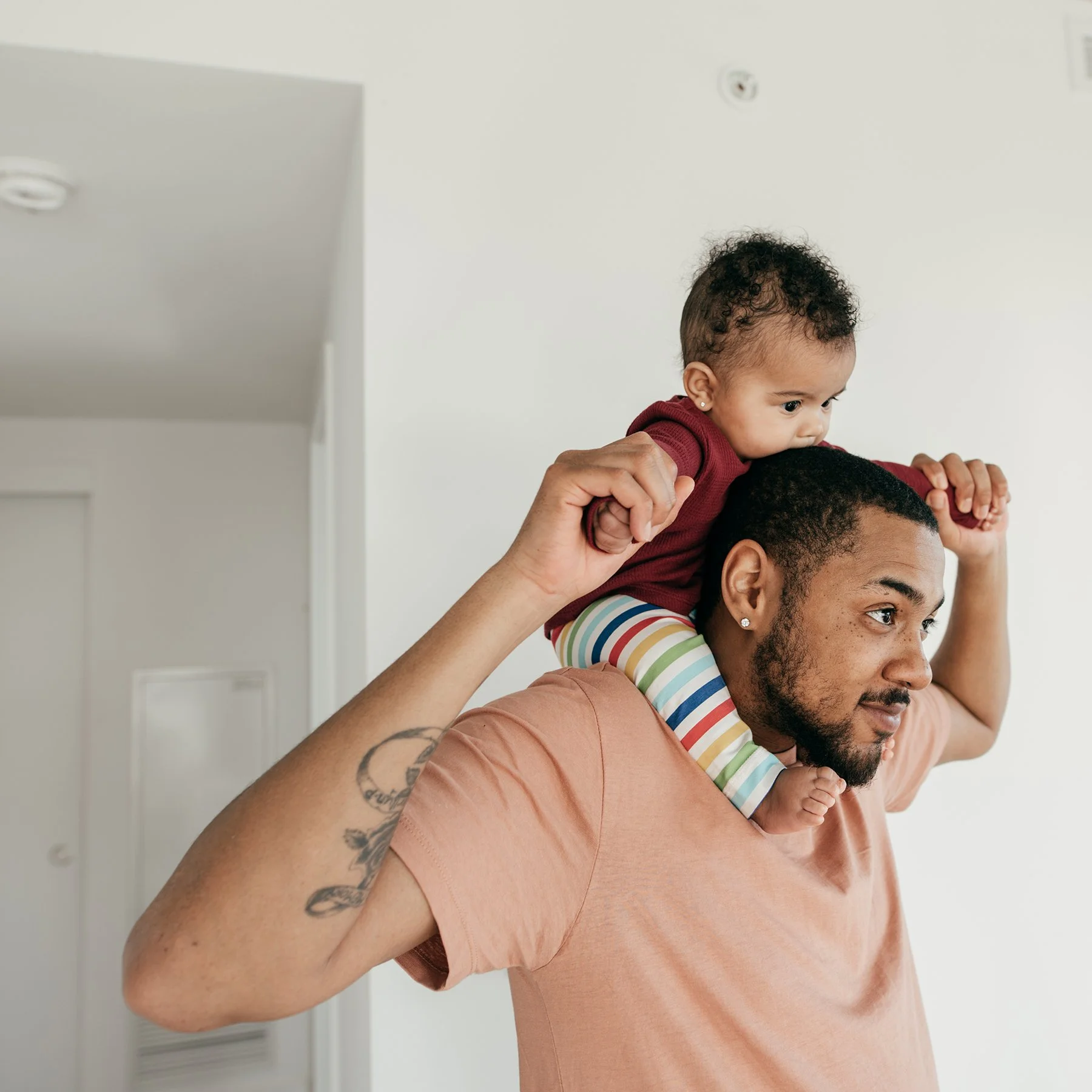 Father holding his newborn baby on his shoulders.