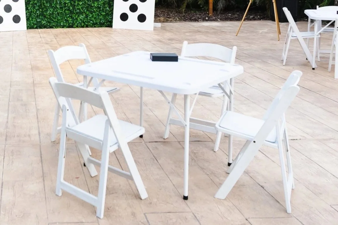White domino table with four white cushion chairs and domino game set