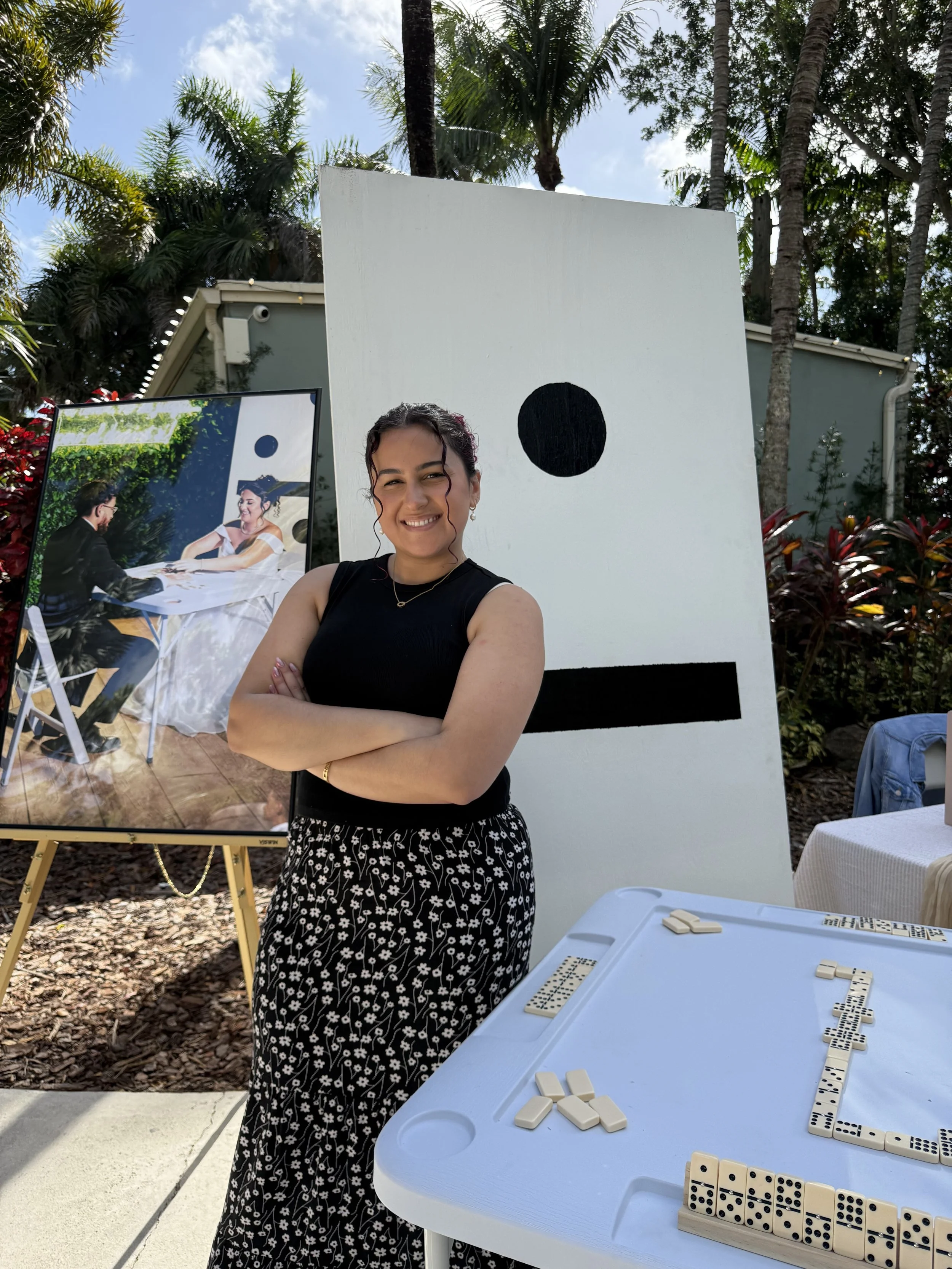 Woman in front of large domino replica crossing her arms and smiling