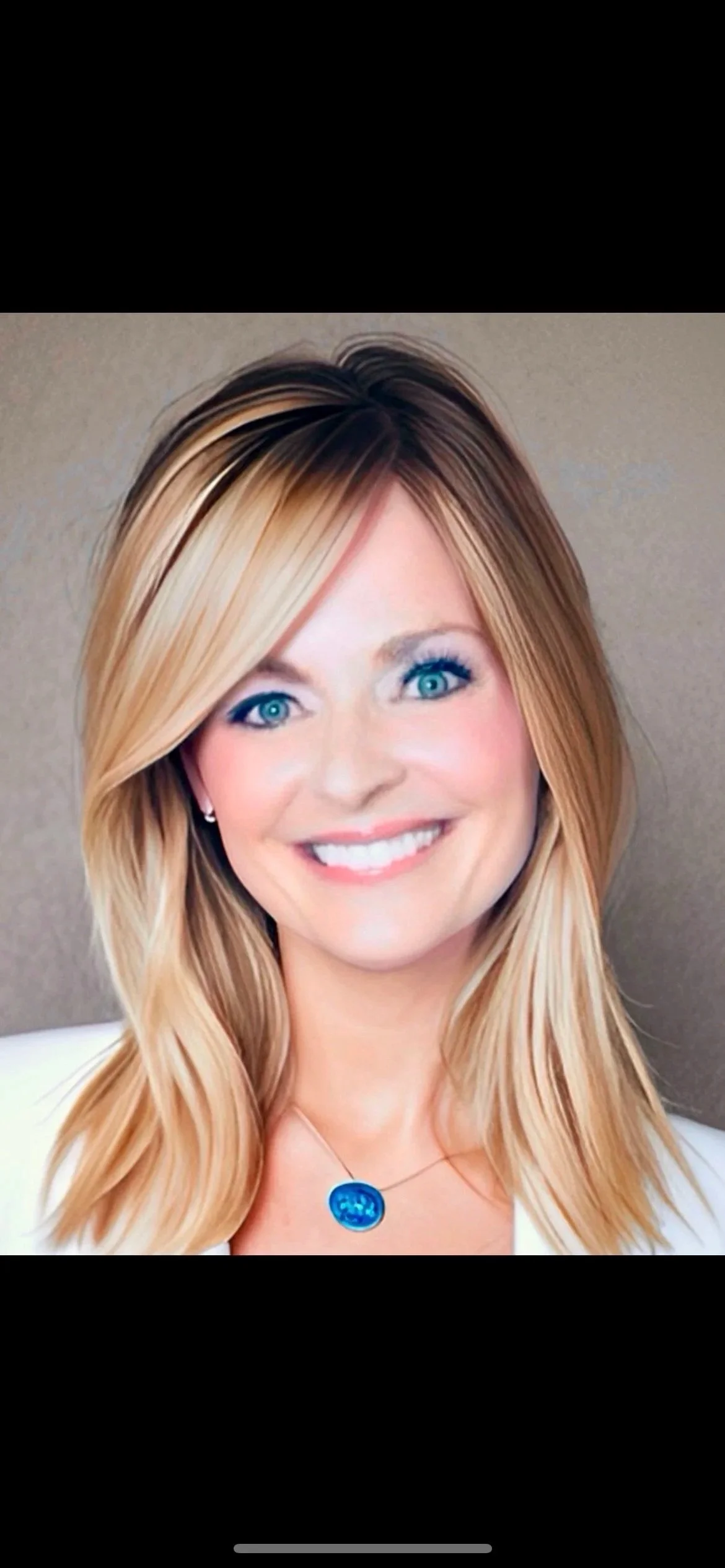 Close-up portrait of a smiling woman with blonde hair and blue eyes, wearing a blue necklace and pearl earrings.