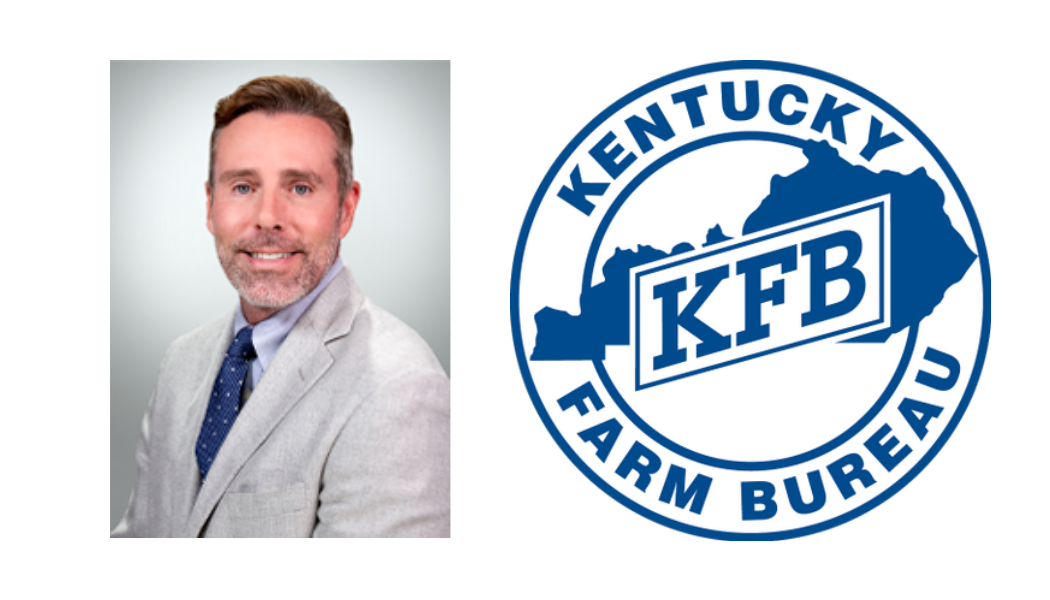 A professional headshot of a middle-aged man with short, light brown hair and a beard, wearing a light gray suit jacket, white shirt, and dark blue tie, standing next to the Kentucky Farm Bureau logo, which features a blue outline of Kentucky with the initials "KFB".