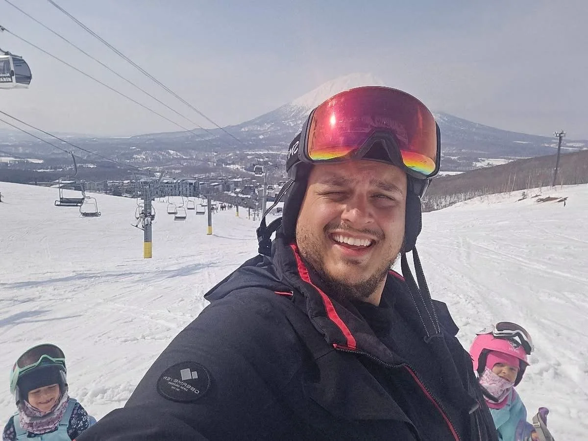 Teddy Collins, Candidate for Colorado SD 4 skiing with his family with a mountain in the background and ski lifts.