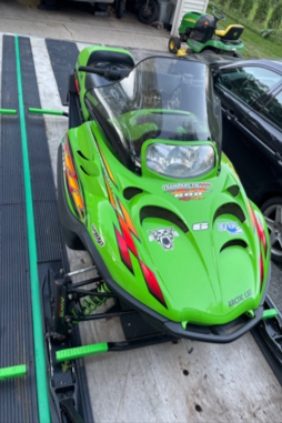 Green racing go-kart with black seat and windshield on a metal track