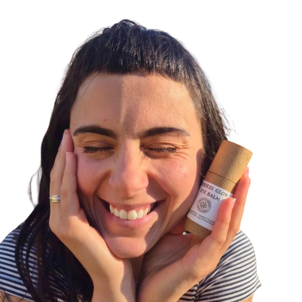 A smiling customer holding the Goddess Glow Eye Balm tube to her cheek