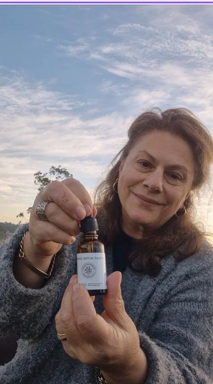 Sonia Karouzos holding a bottle of Wild Goddess Botanicals face oil, outdoors at dusk