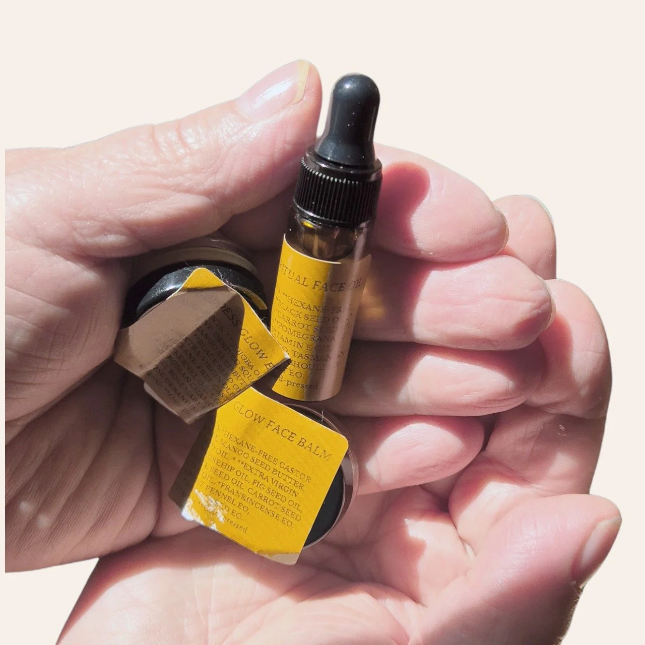The three Ritual Sampler pieces held in a hand - Face Oil, Face Balm and Eye Balm