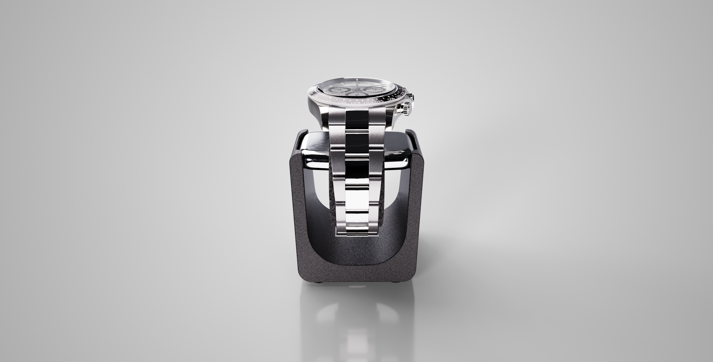 A stainless steel wristwatch with a black bezel and a bracelet band, placed on a black watch stand against a plain gray background.