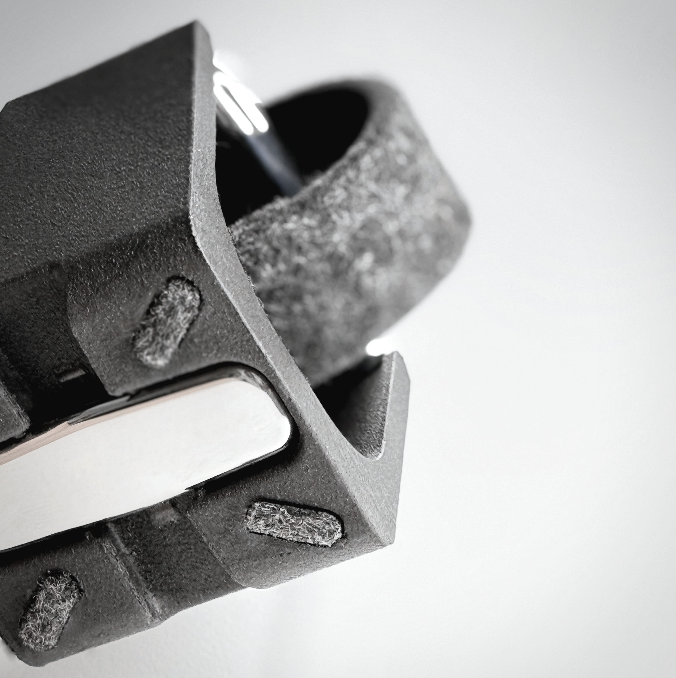 Close-up of the bottom of the Watch.sys holder with the spacer assembled in the bottom, showing textured edges of the base and a gray felt surface of the carrier.