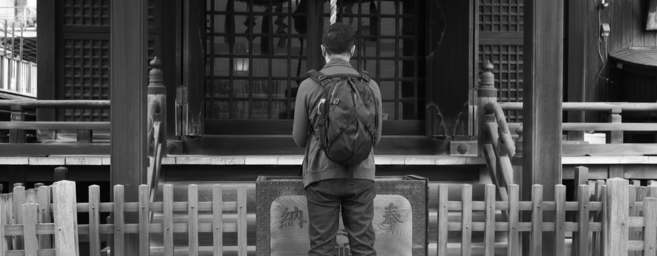 A black and white photograph of Randy Yang in quiet reflection before a Japanese Shinto shrine. The image serves as a metaphor for the design process: achieving clarity in complex hardware development requires a state of calm and the right collaborat