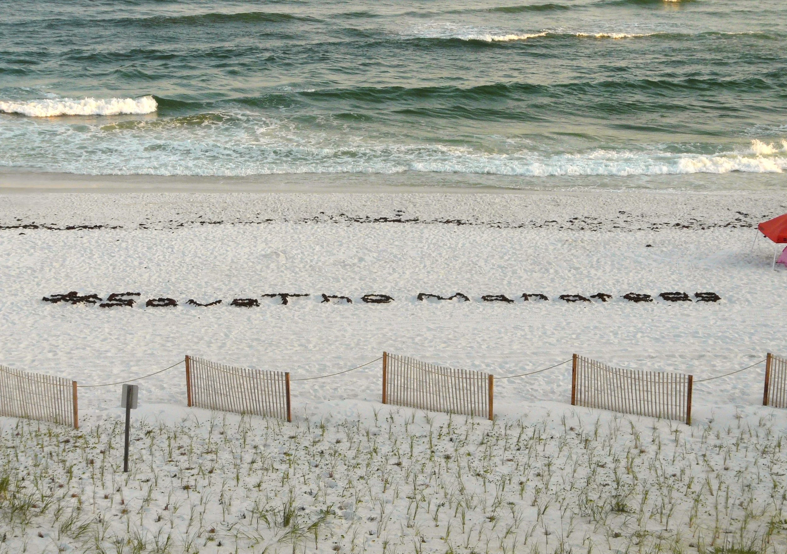 #SaveThe Manatees written on the sand in Fort Walton Beach, Florida.