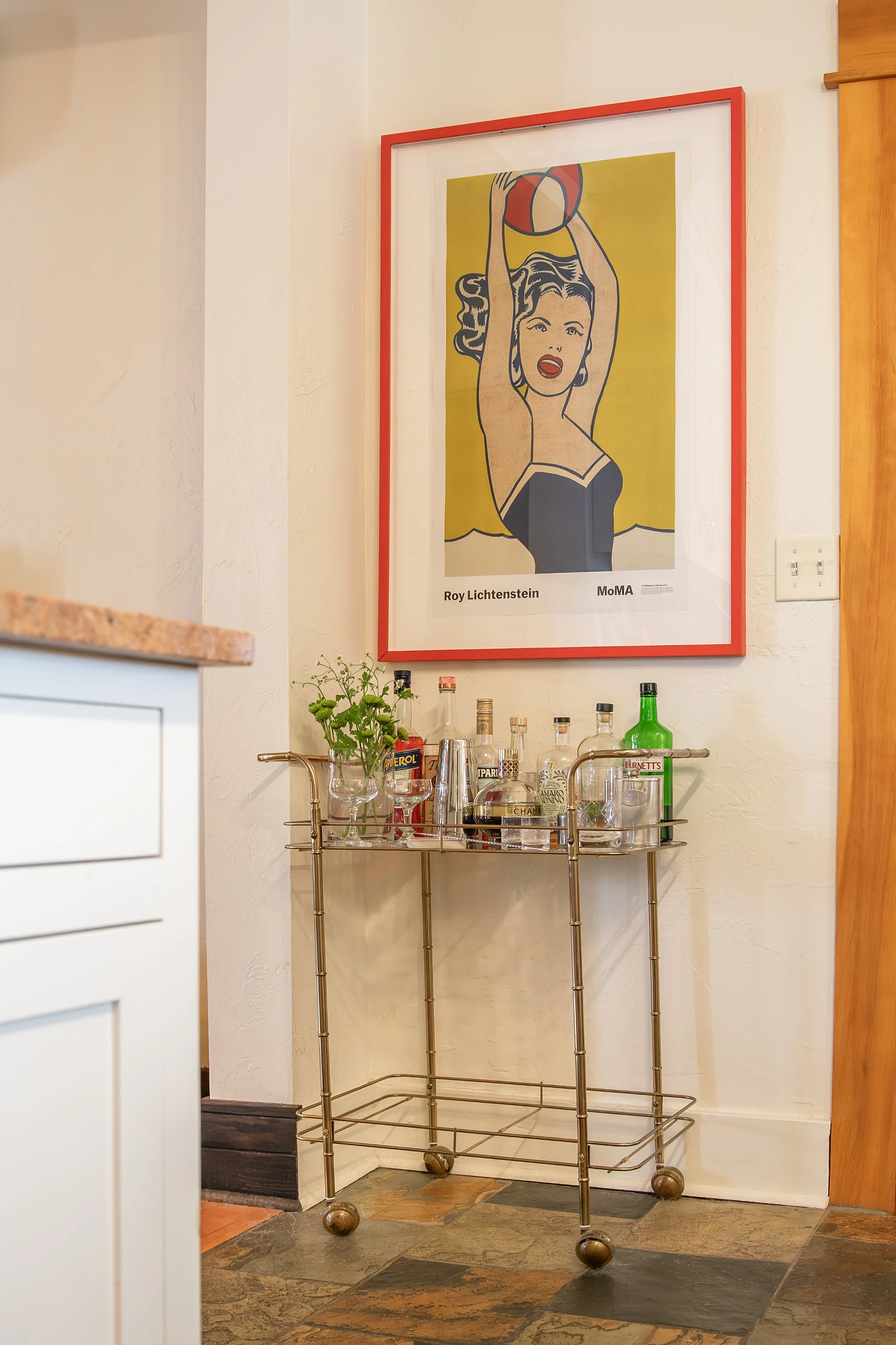 A bar cart with various liquor bottles, glassware, and a small plant. Bozeman interior design, interior renovation, and interior styling. 