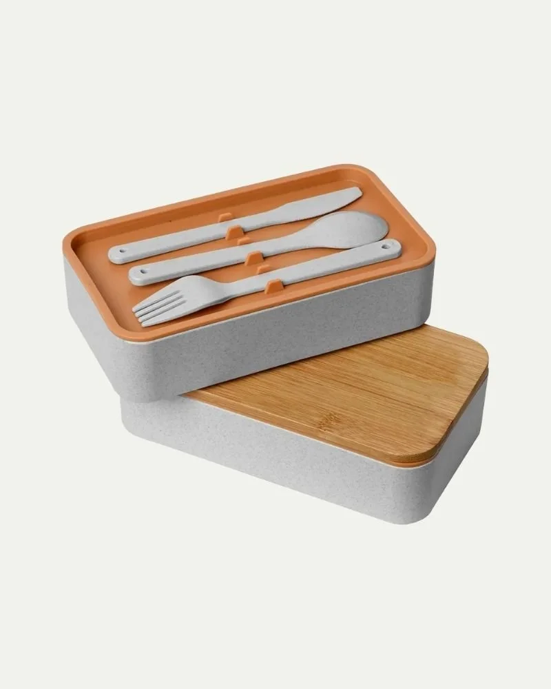 A set of gray utensils including a knife, spoon, and fork stored in an orange and gray case placed on a wooden lid.