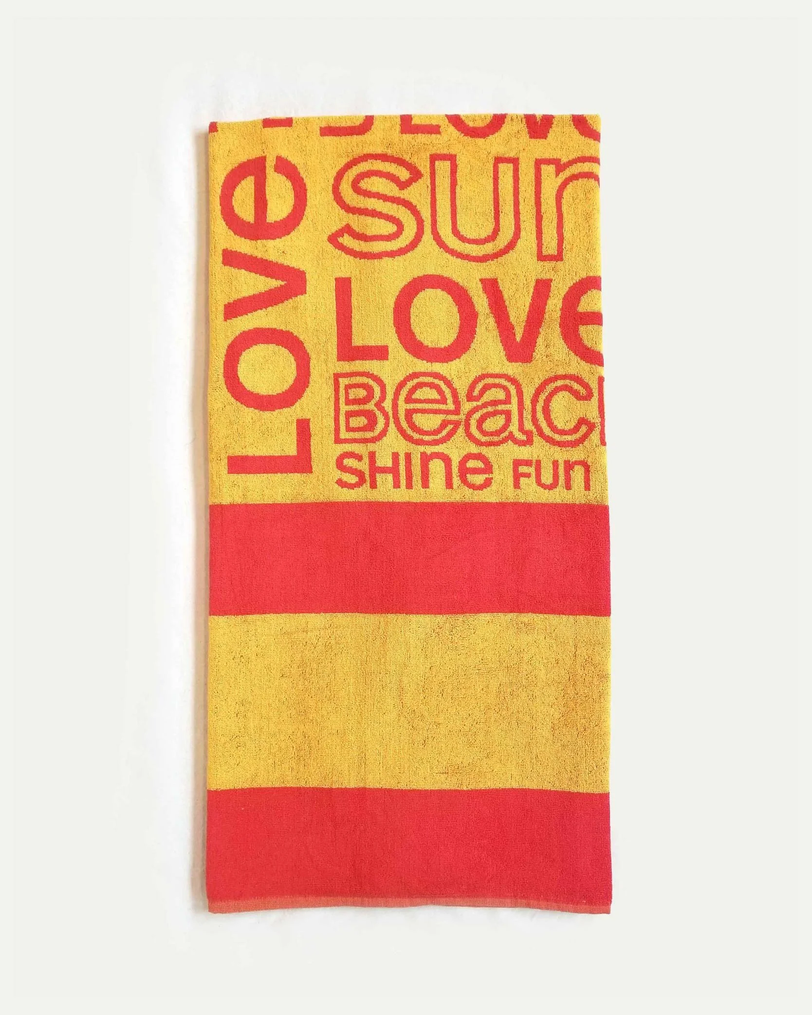 Yellow towel with red stripes and red text reading 'LOVE', 'sun', 'LUV', 'BEACH', 'SHINE', and 'FUN'.