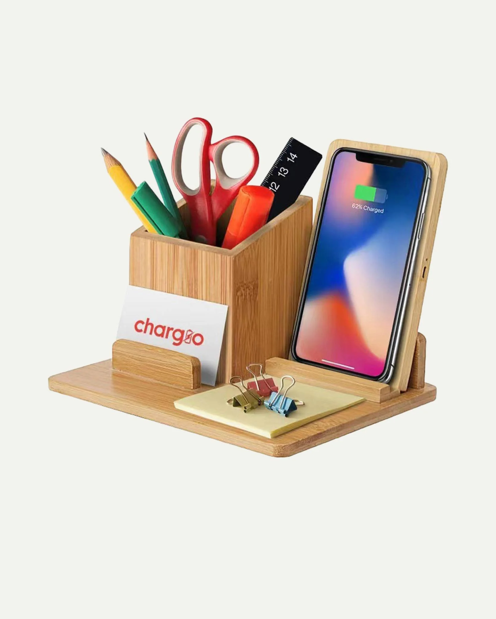 Wooden desk organizer holding writing utensils, scissors, ruler, sticky notes, paper clips, and a smartphone charging dock with a smartphone. A small card with 'charge' is attached to the organizer.