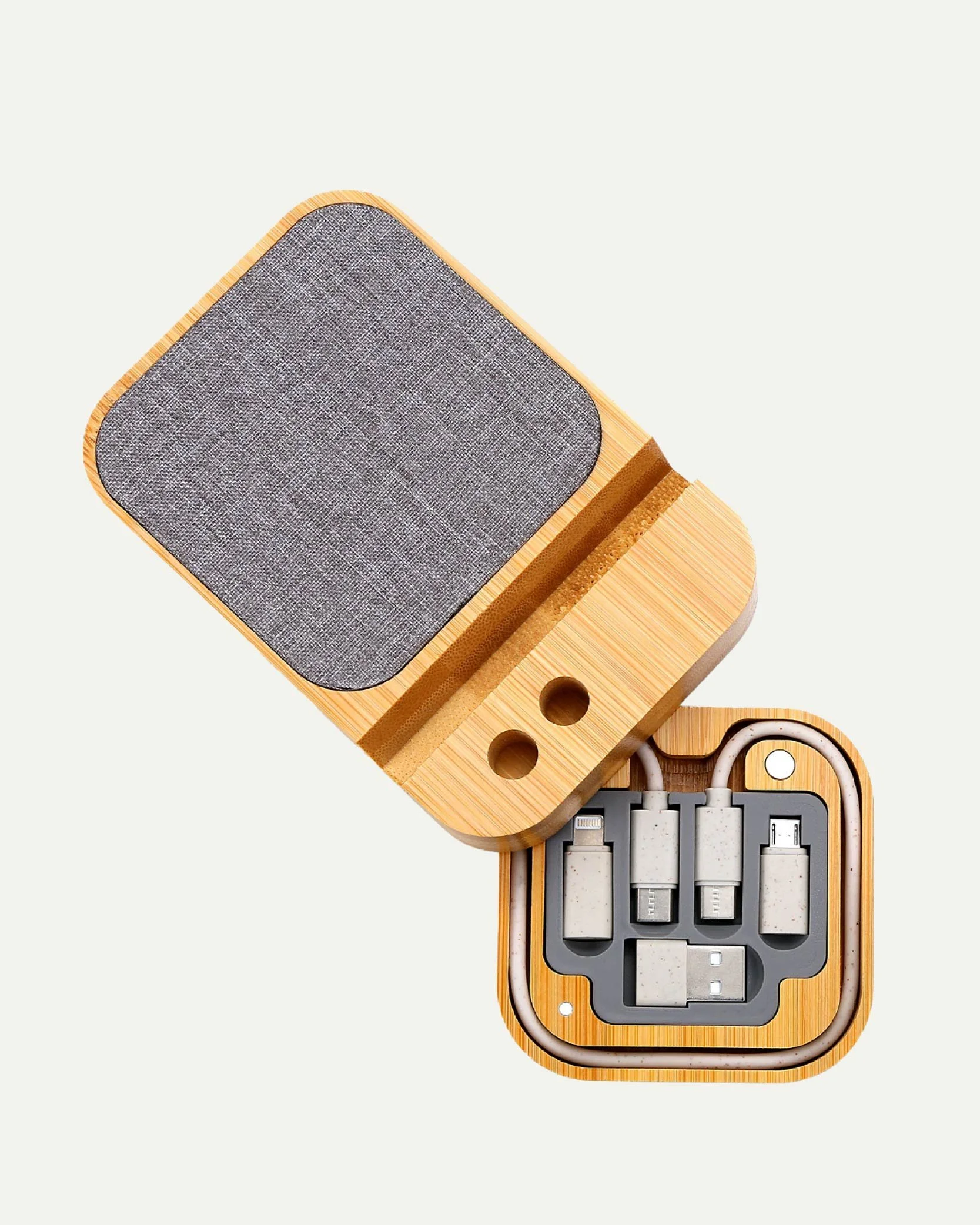 A wooden charging dock with a fabric-covered pad on top and six port slots at the bottom, housing various cables and adapters.