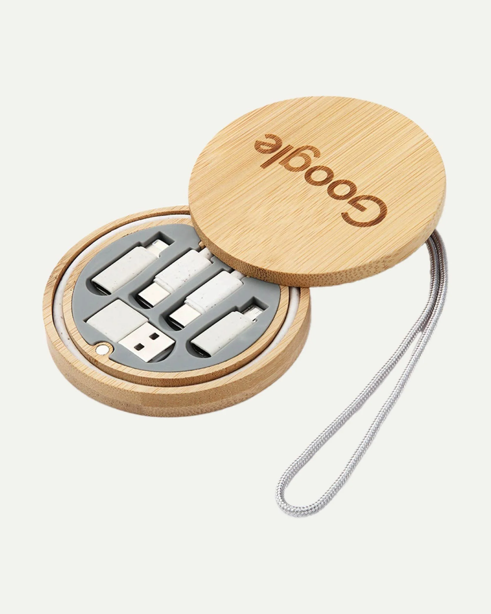 A round wooden box with a sliding lid labeled 'Groupe' contains multiple charging cables and adapters, with a silver cord attached.