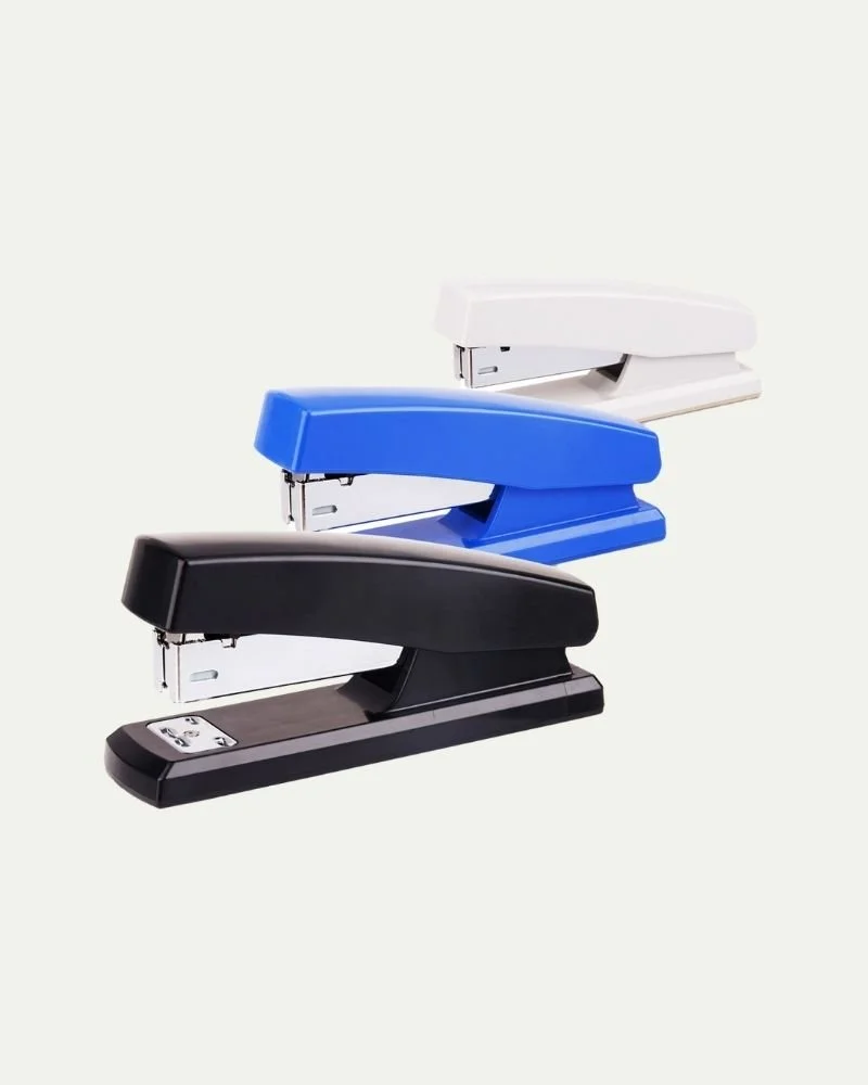 Three staplers in black, blue, and white, stacked diagonally against a plain light background.