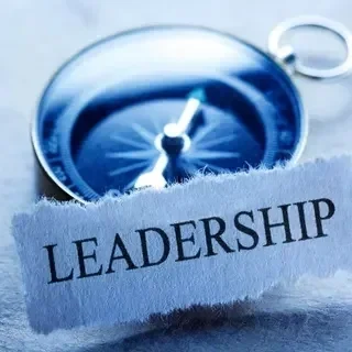 A compass partially covered by a torn piece of paper with the word 'LEADERSHIP' on it.