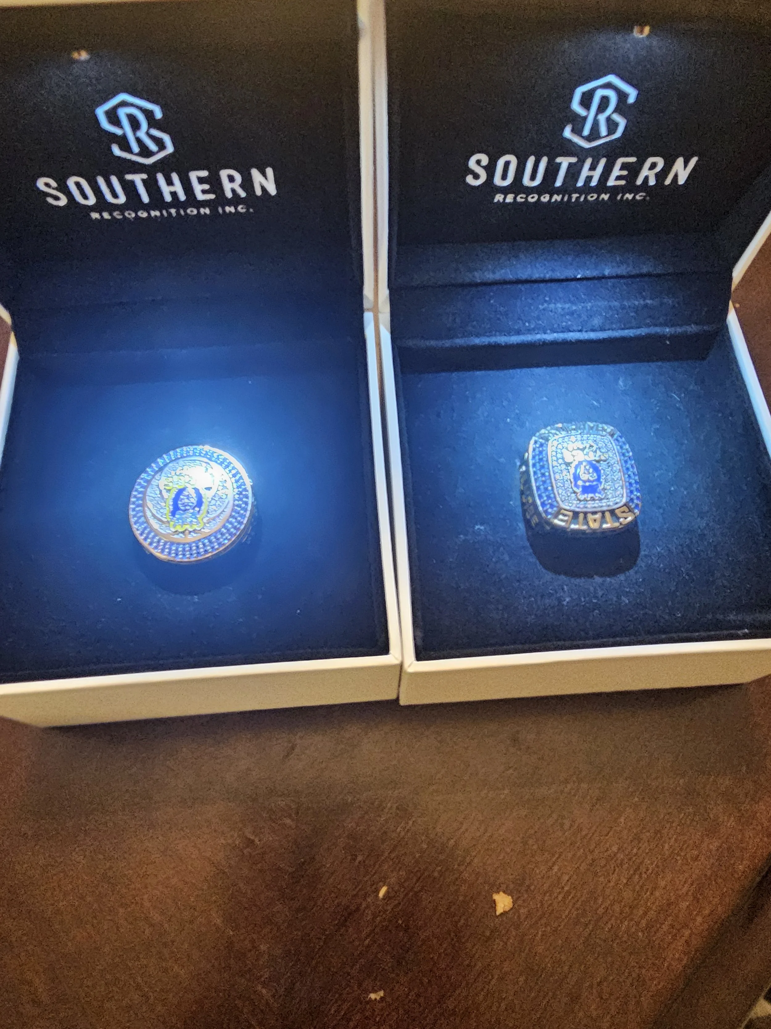 Two boxes with Southern Recognition Inc. branding, each containing a ring with a congressional seal illuminated by a blue light.