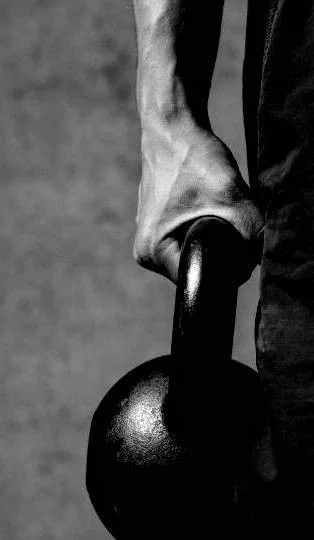 A person's hand gripping a kettlebell.