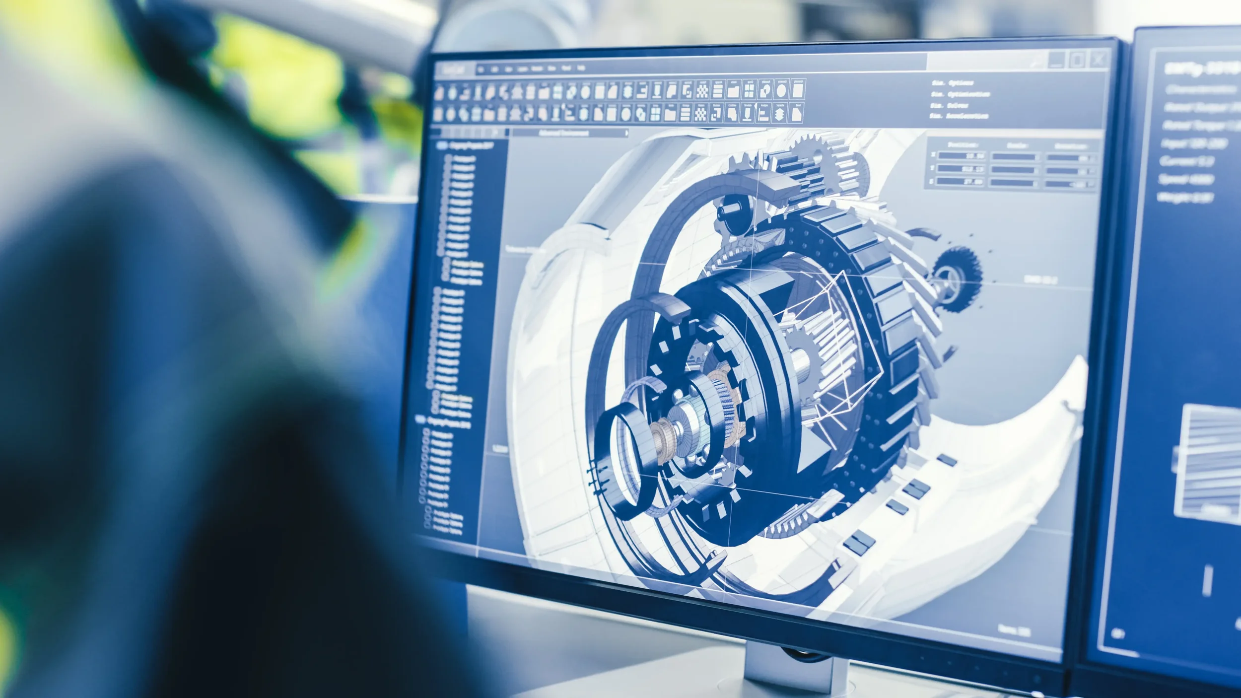 Computer monitor displaying technical CAD design of a gear assembly in a 3D modeling software.