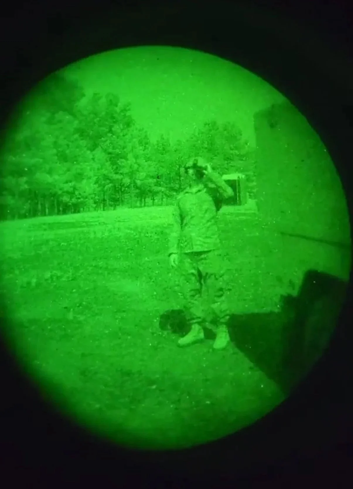A person in military pvs14 pulling security  at night through a green phosphor NVG.