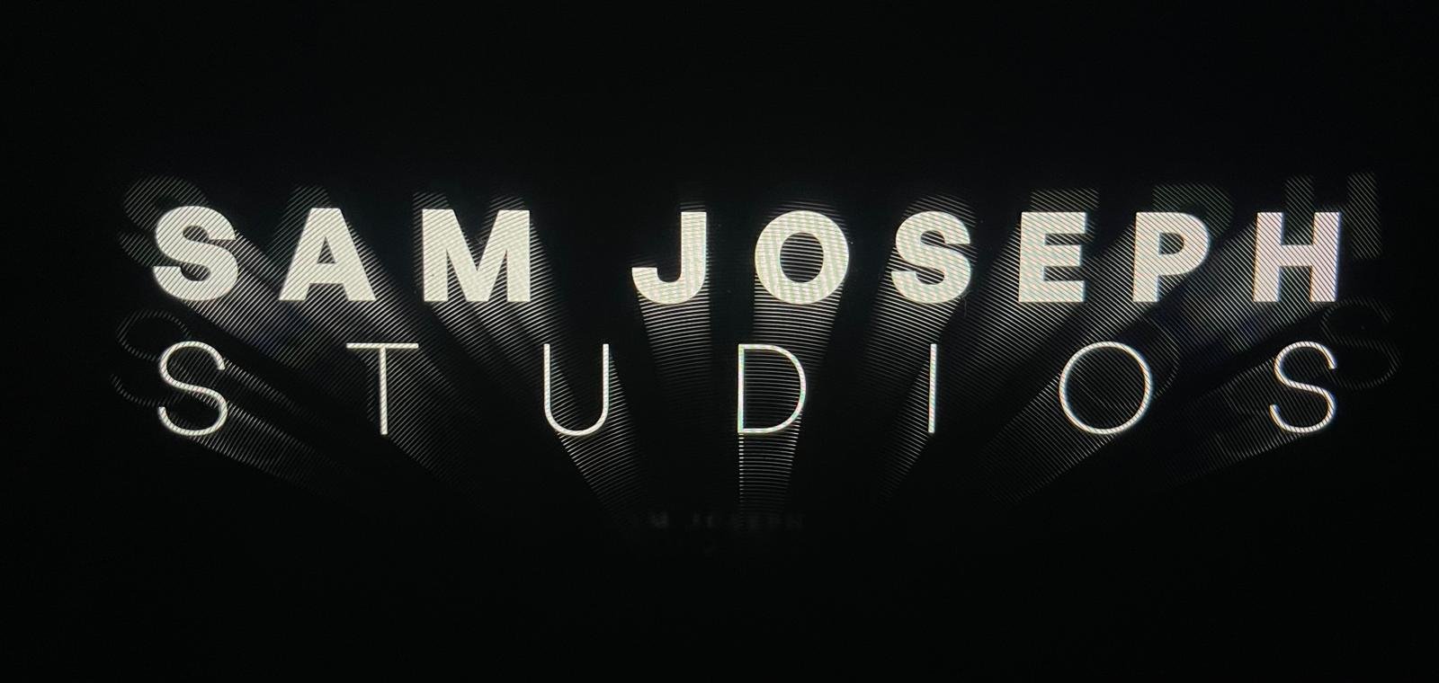 Neon sign displaying the words "Sam J. Joseph Studios" on a black background.